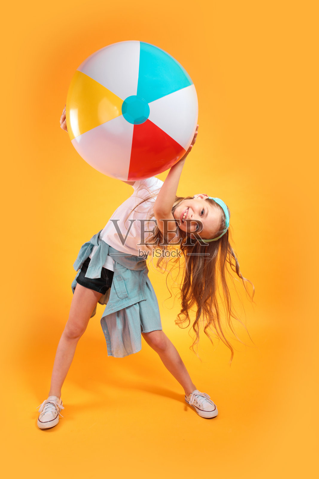 有趣的快乐的孩子在夏天的衣服跳跃与彩色背景的沙滩球照片摄影图片