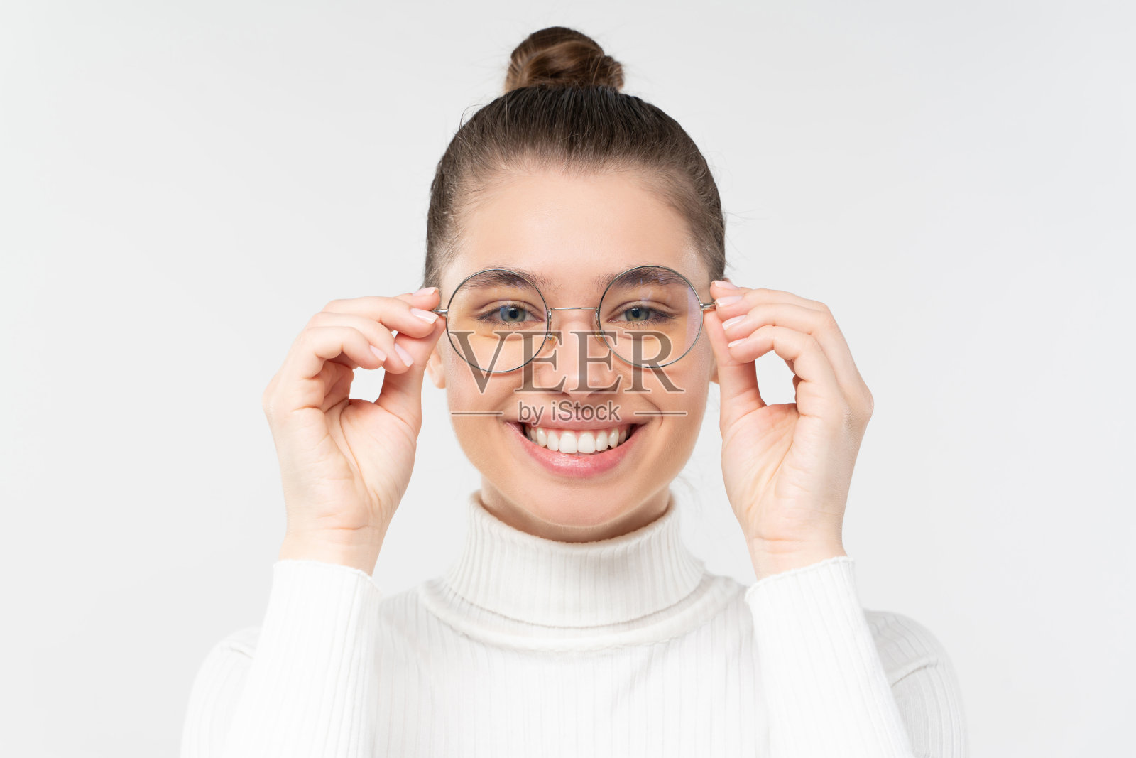 年轻女子戴着眼镜，面带微笑，直视相机，感觉轻松和满意，良好的视力，孤立在灰色的背景照片摄影图片