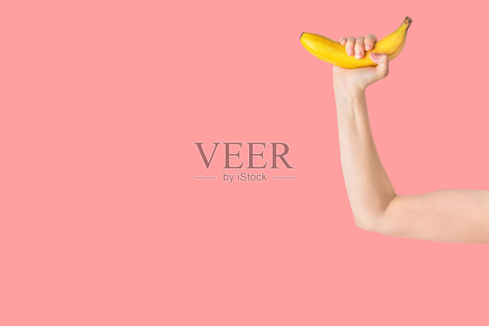 年轻的白人女孩手拿香蕉模仿哑铃锻炼肌肉。健康、积极的生活方式、纯素饮食、健身理念照片摄影图片