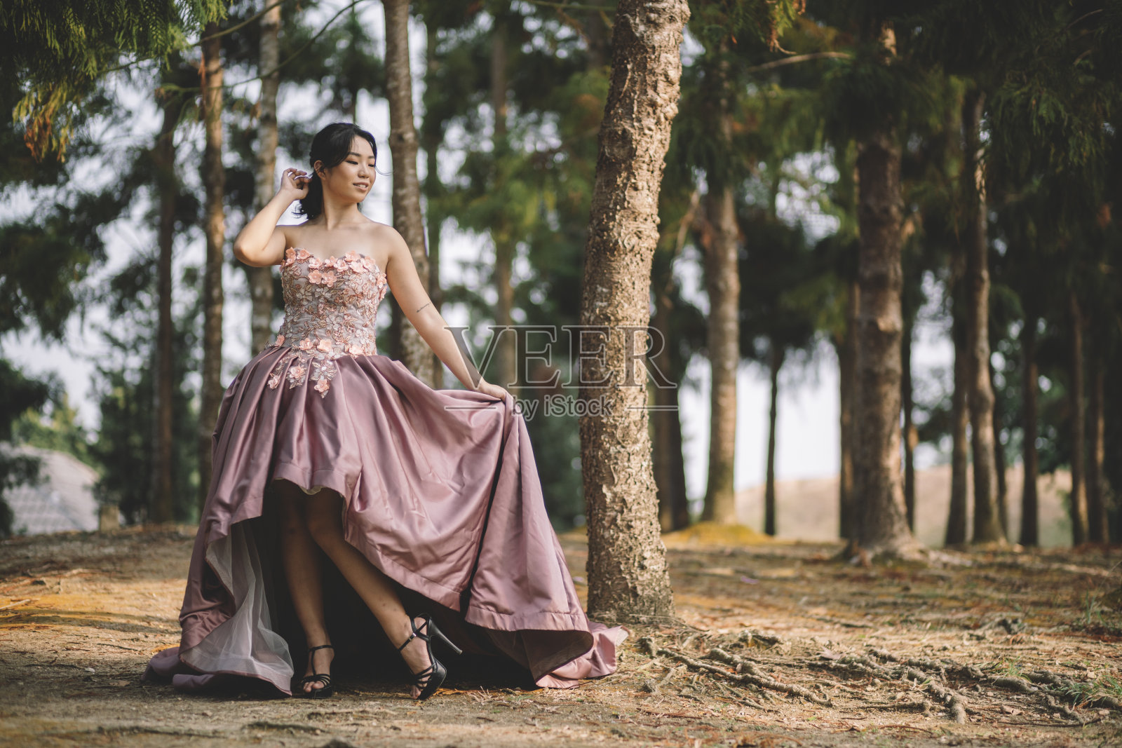年轻的亚洲华人新娘穿着粉红色婚纱在公园摆姿势照片摄影图片