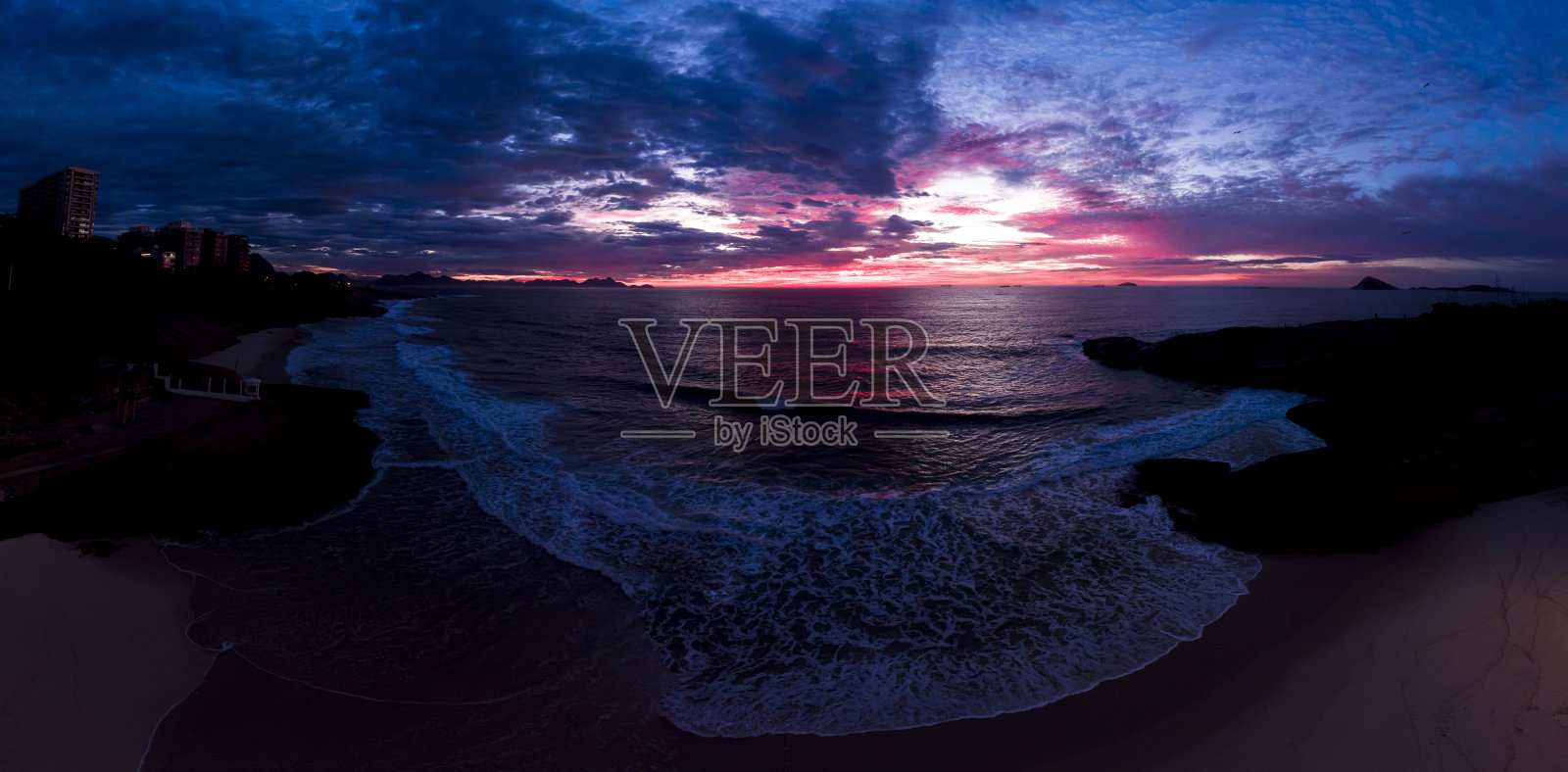 在里约热内卢的Arpoador Devil的海滩上，太阳落山前五颜六色的破晓时分，一股巨浪袭来照片摄影图片
