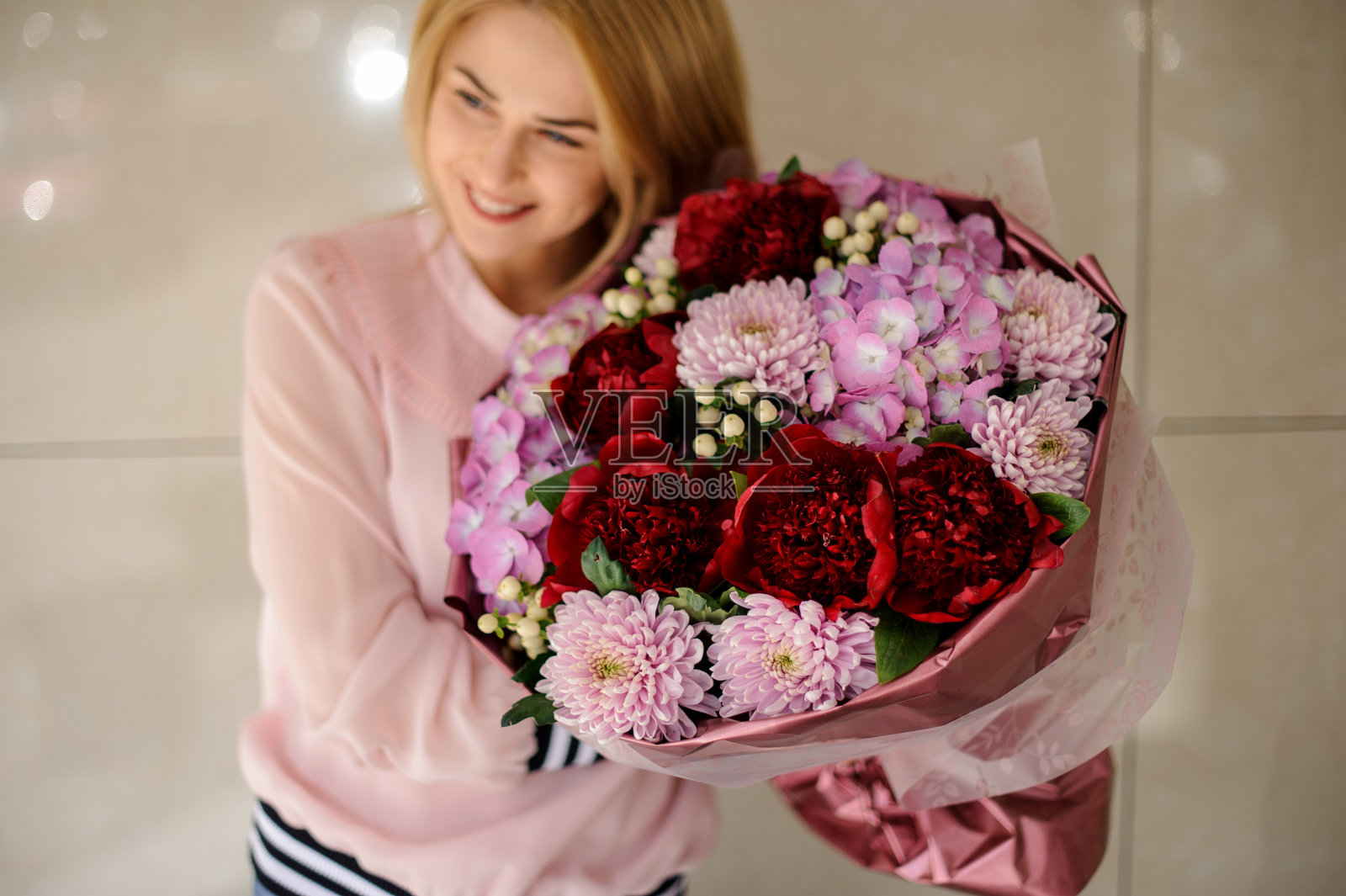 漂亮女人捧着一束新鲜的牡丹、绣球花、菊花。照片摄影图片