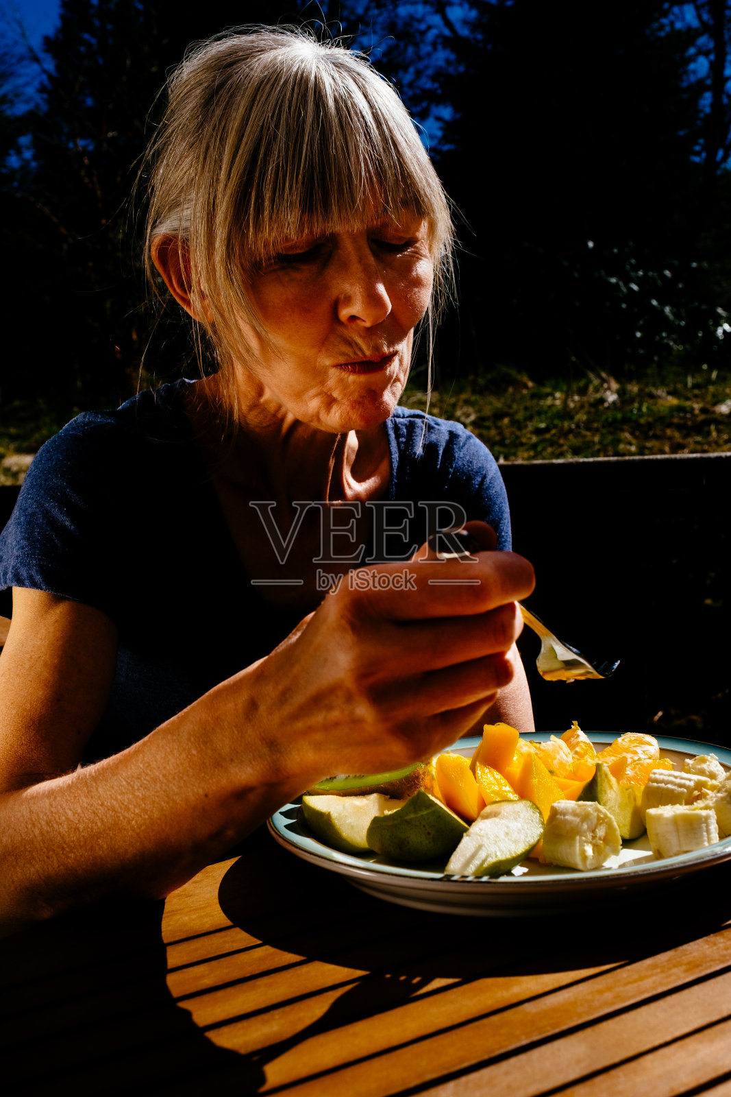 老妇人在院子里吃水果沙拉照片摄影图片