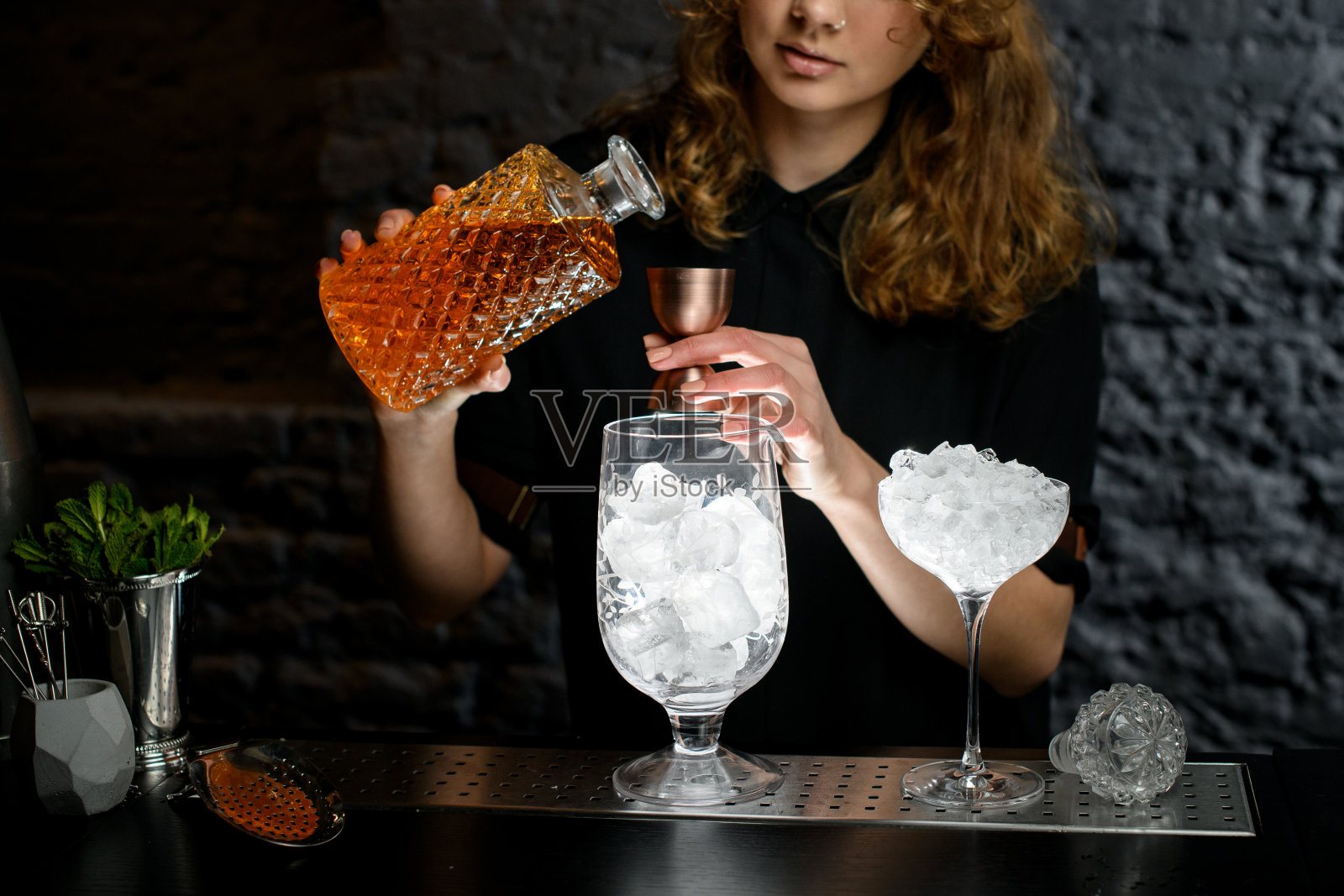 女调酒师将酒从酒瓶中倒入杯中。照片摄影图片