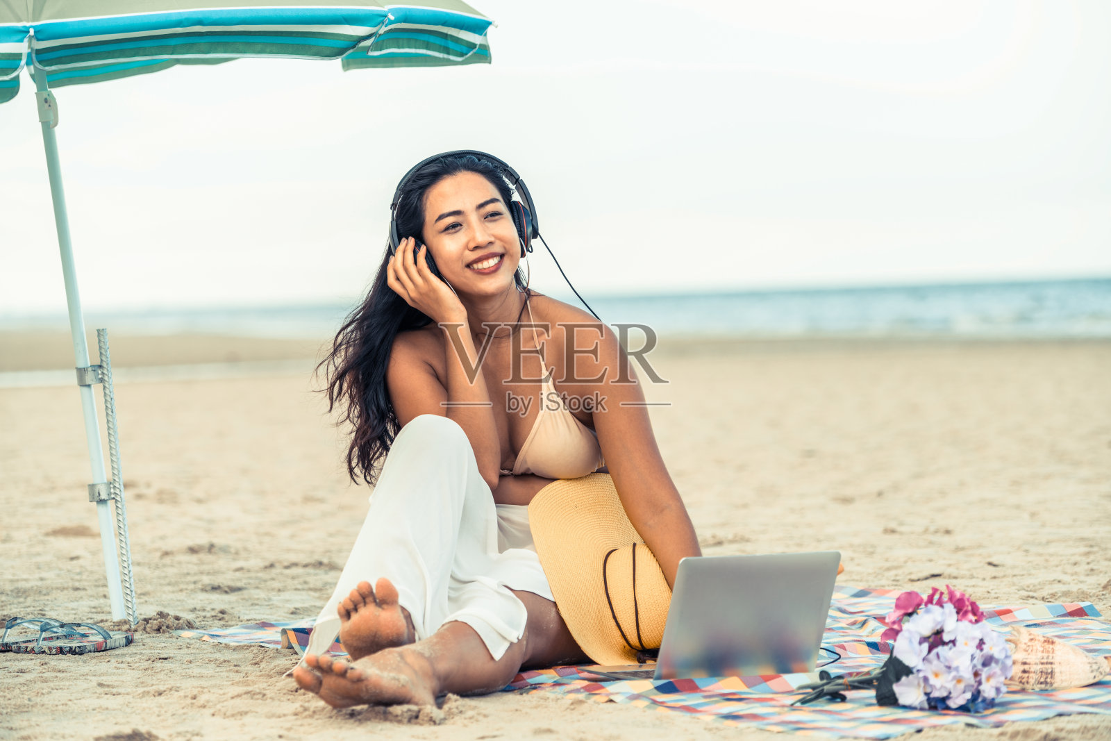 坐在海滩上的大号年轻女人。照片摄影图片