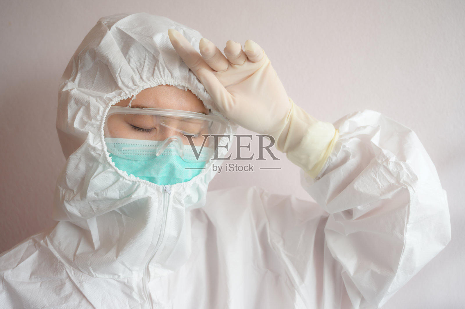 身穿防护服防护冠状病毒病时出现头痛和疲劳的护士。照片摄影图片