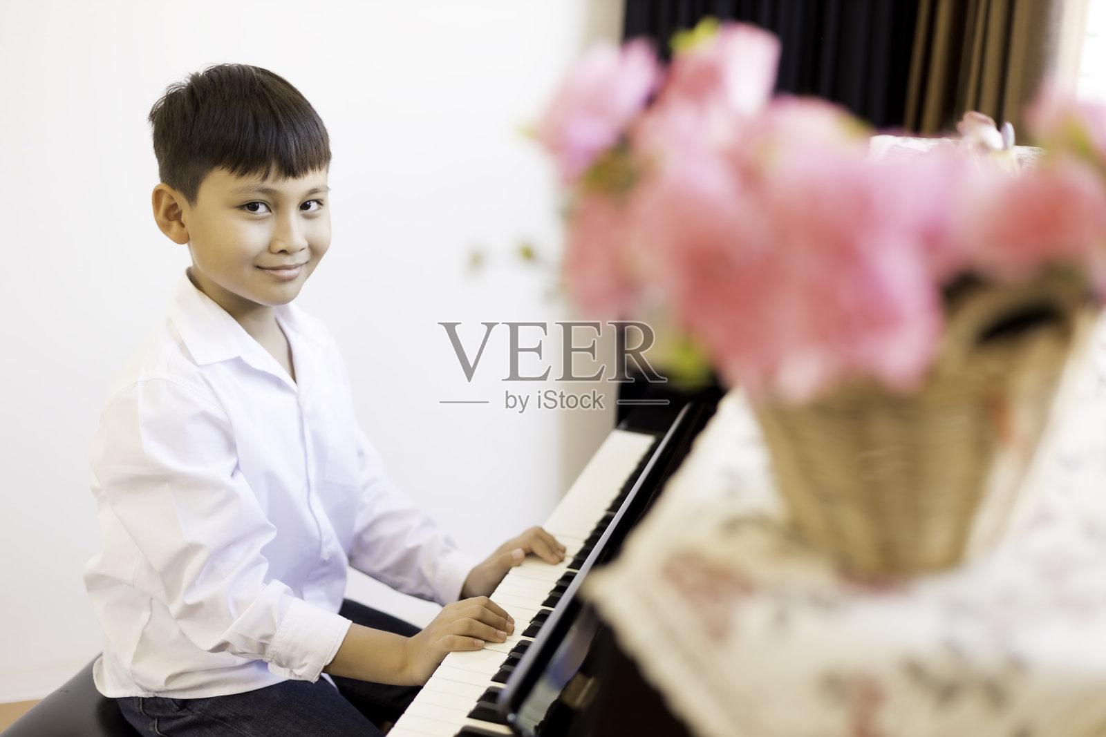 一个亚洲男孩在音乐教室里练习弹钢琴。照片摄影图片