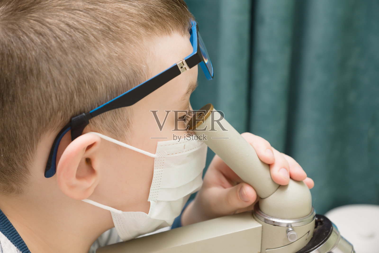 戴着防护面具的男孩在研究显微镜照片摄影图片