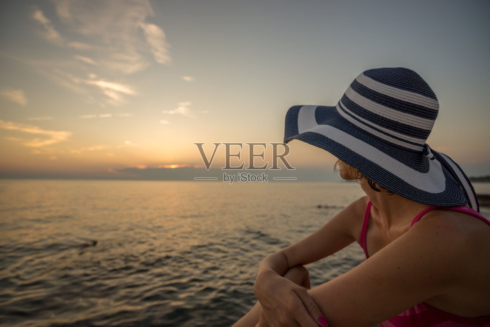 女人在一个时髦的草帽放松在海滩上看海洋照片摄影图片