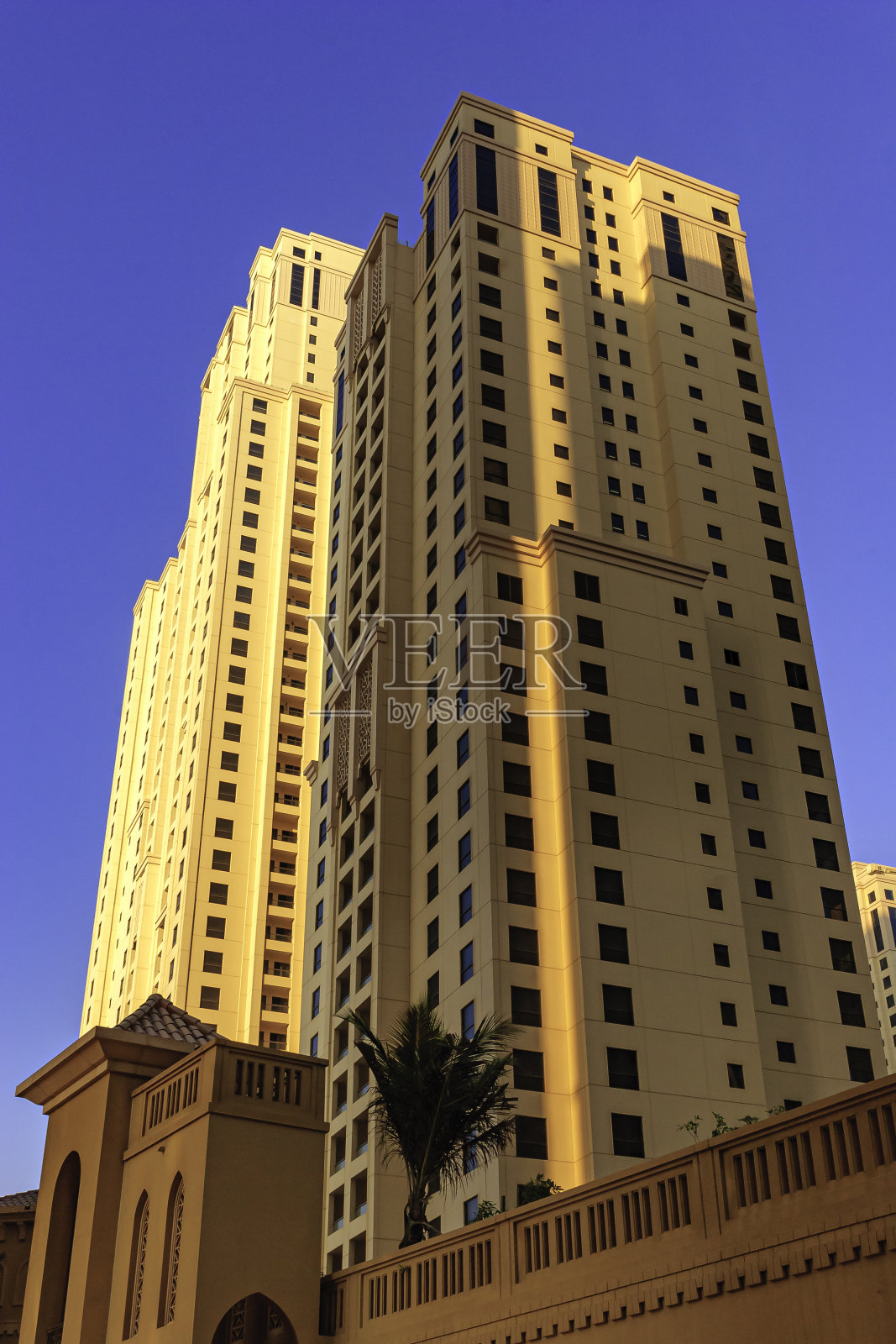 阿拉伯联合酋长国迪拜——仰望城市中朱美拉海滩住宅的一些塔的顶端，在晴朗的蓝色夜空下;垂直格式照片摄影图片