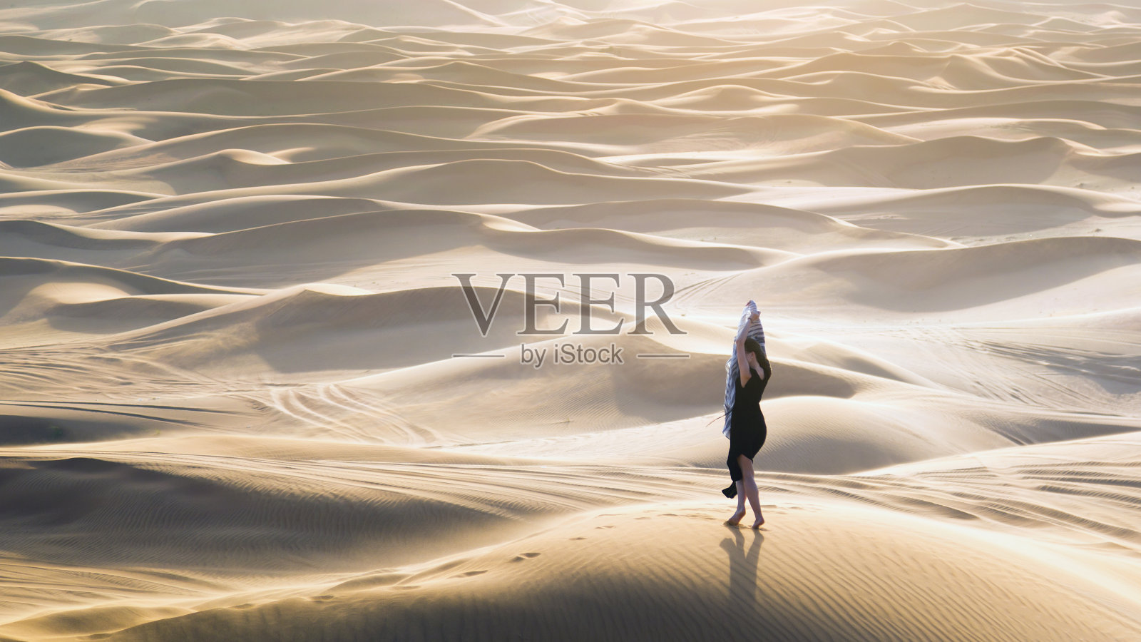 广袤沙漠背景下的女性剪影。照片摄影图片