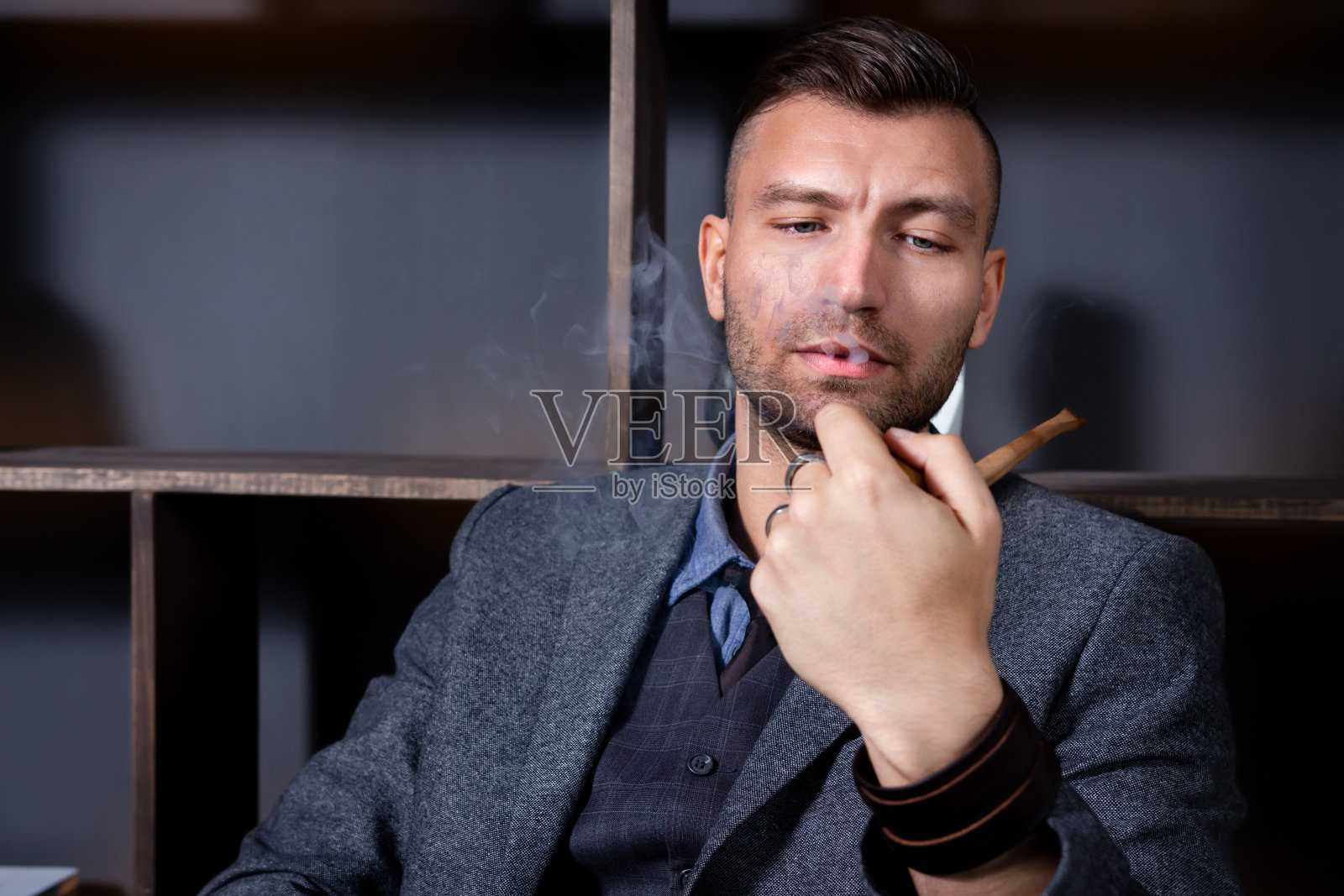 一幅优雅男子的肖像，坐在扶手椅上，在他的办公室里抽烟照片摄影图片