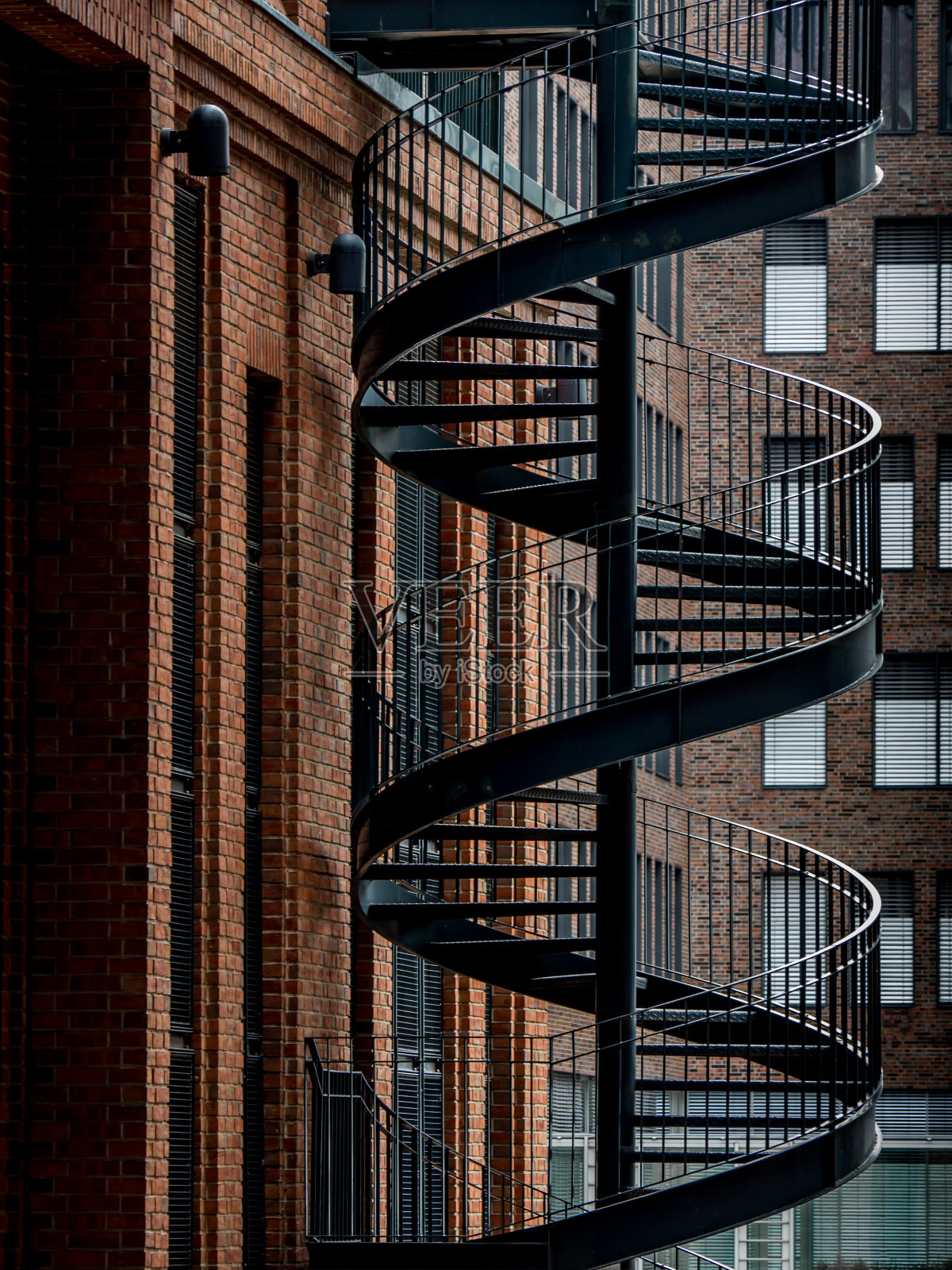 工业设计中的钢螺旋楼梯的正面视图，通向一个现代后院的办公大楼外的砖立面照片摄影图片
