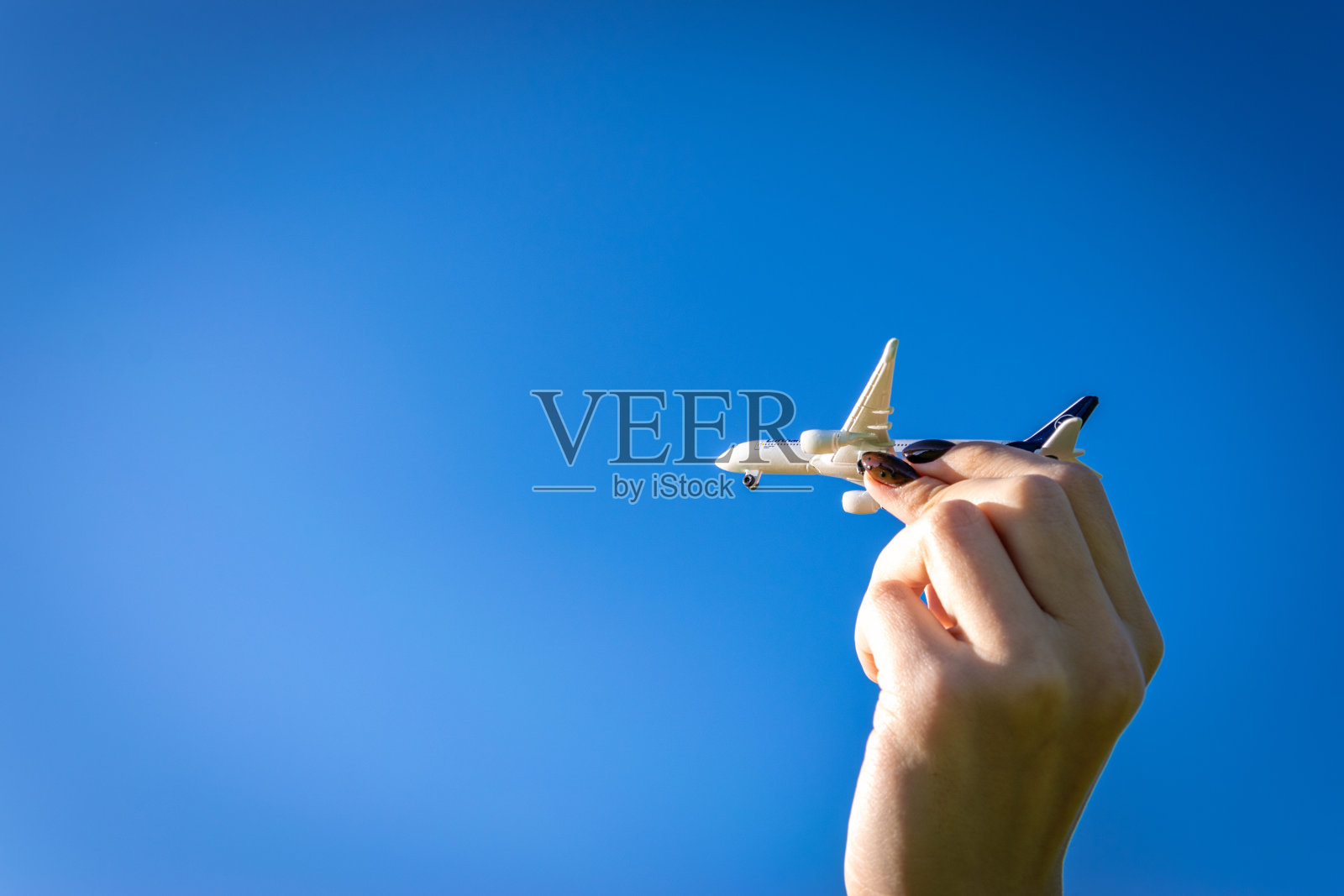 飞机白色玩具上的阳光背景。女人手中明亮的飞机在阳光天空中飞行。飞机在空中飞行的概念。照片摄影图片