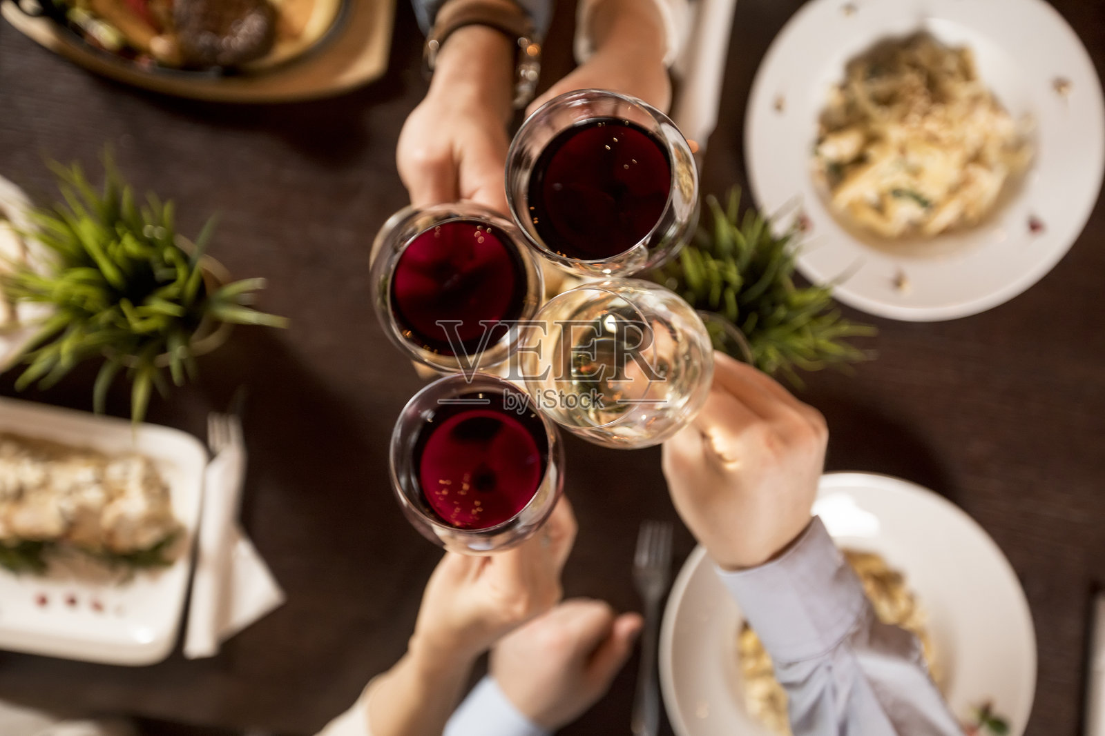 四手拿红酒在上桌的食物上祝酒照片摄影图片
