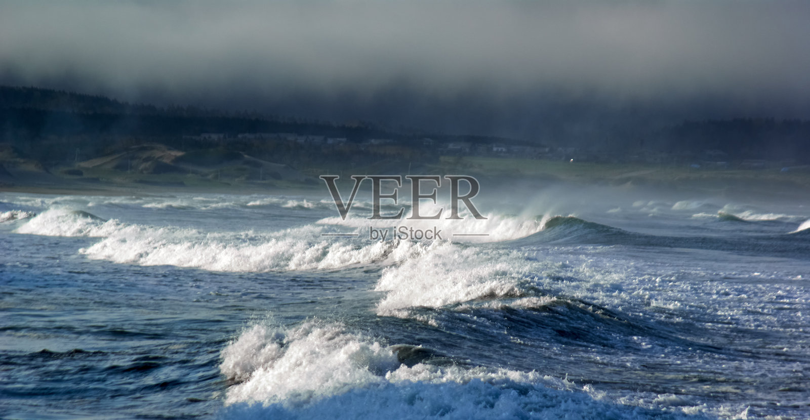 暴风雨的海浪拍打着海岸的海滩，阳光和风照片摄影图片