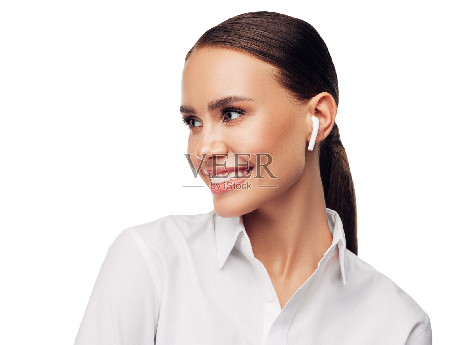 商业女孩的大头照穿白衬衫，无线耳机，看着与友好自信的微笑，孤立在白色的背景照片摄影图片