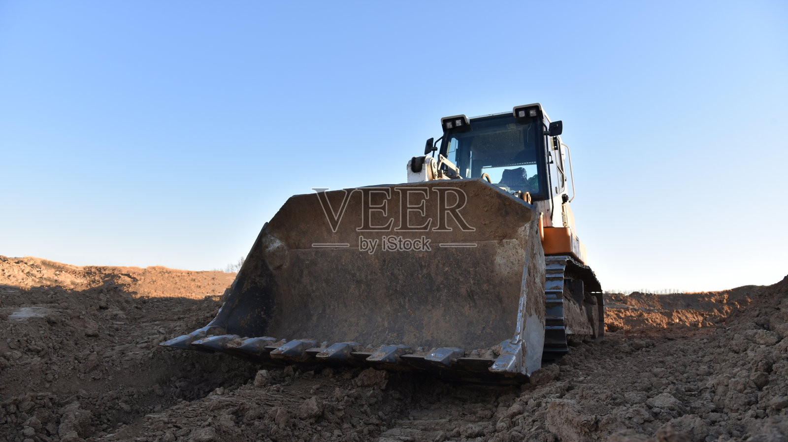 履带式装载机在工地铲土。用于清理土地、平整、挖池、公用事业挖沟和挖掘基础的土方设备。采石场的履带式装载机或推土机照片摄影图片