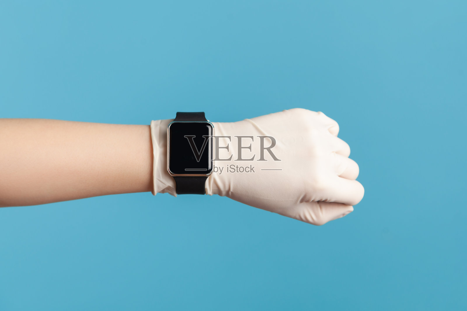 侧面特写的人的手在白色外科手套持有和显示手腕智能手表屏幕。照片摄影图片
