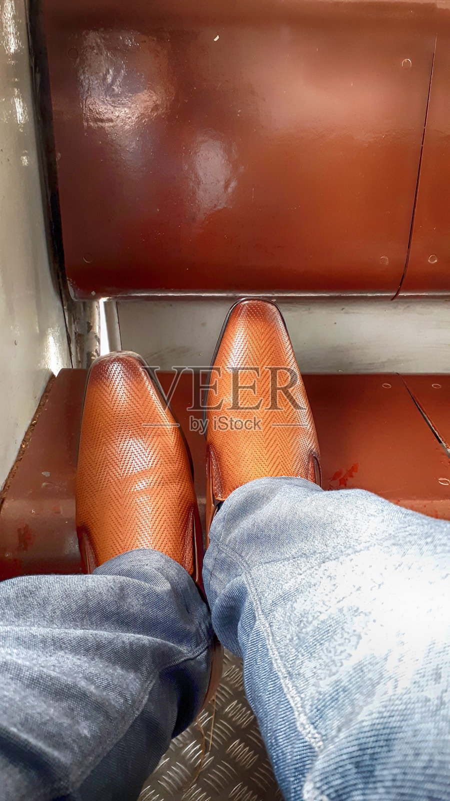 这是一个男人穿着一双棕色的鞋子在火车旅行的照片。照片摄影图片