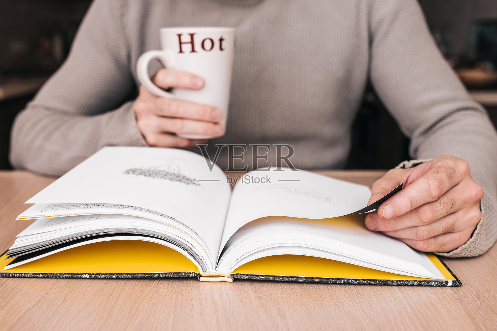一个人在图书馆的桌子旁看书，手里拿着一个杯子照片摄影图片