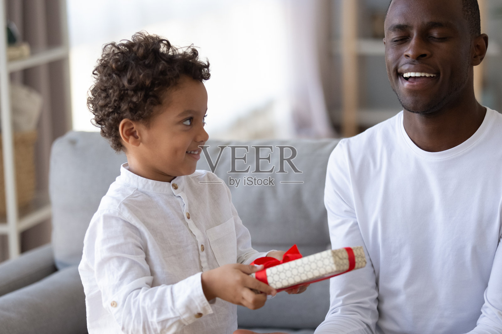 小儿子为微笑的非裔美国父亲制作惊喜礼物照片摄影图片