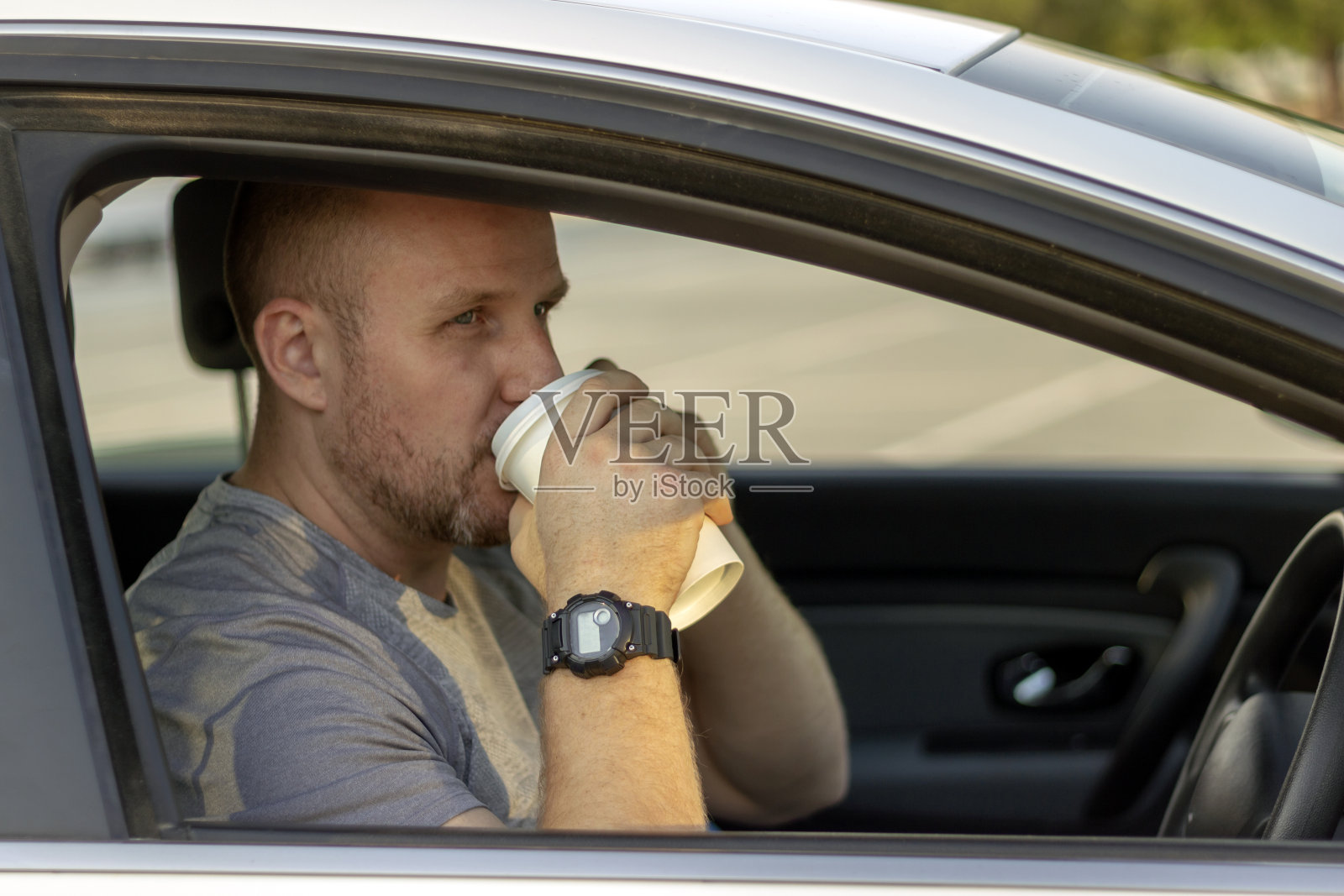 微笑的男人一边喝着咖啡一边开车。照片摄影图片