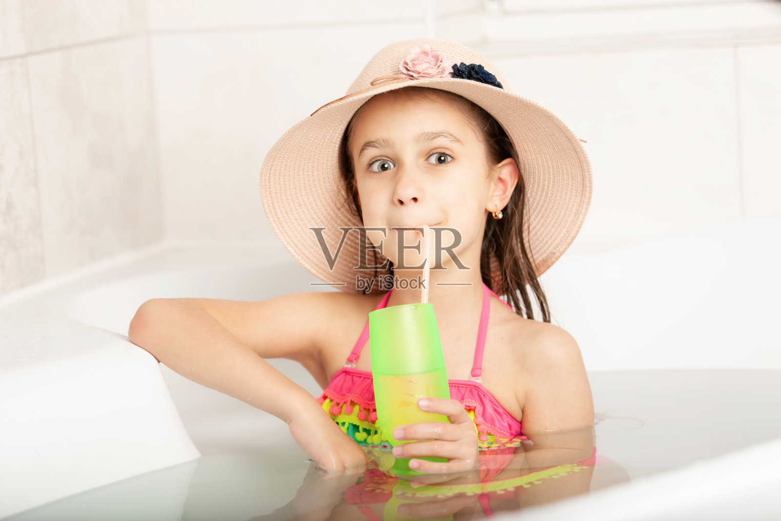 有趣的小白种漂亮女孩戴着帽子在家里玩沙滩游泳照片摄影图片