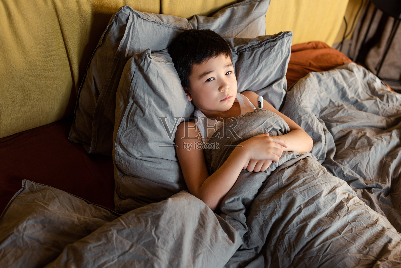 悲伤生病的亚洲男孩与体温计躺在床上自我隔离照片摄影图片