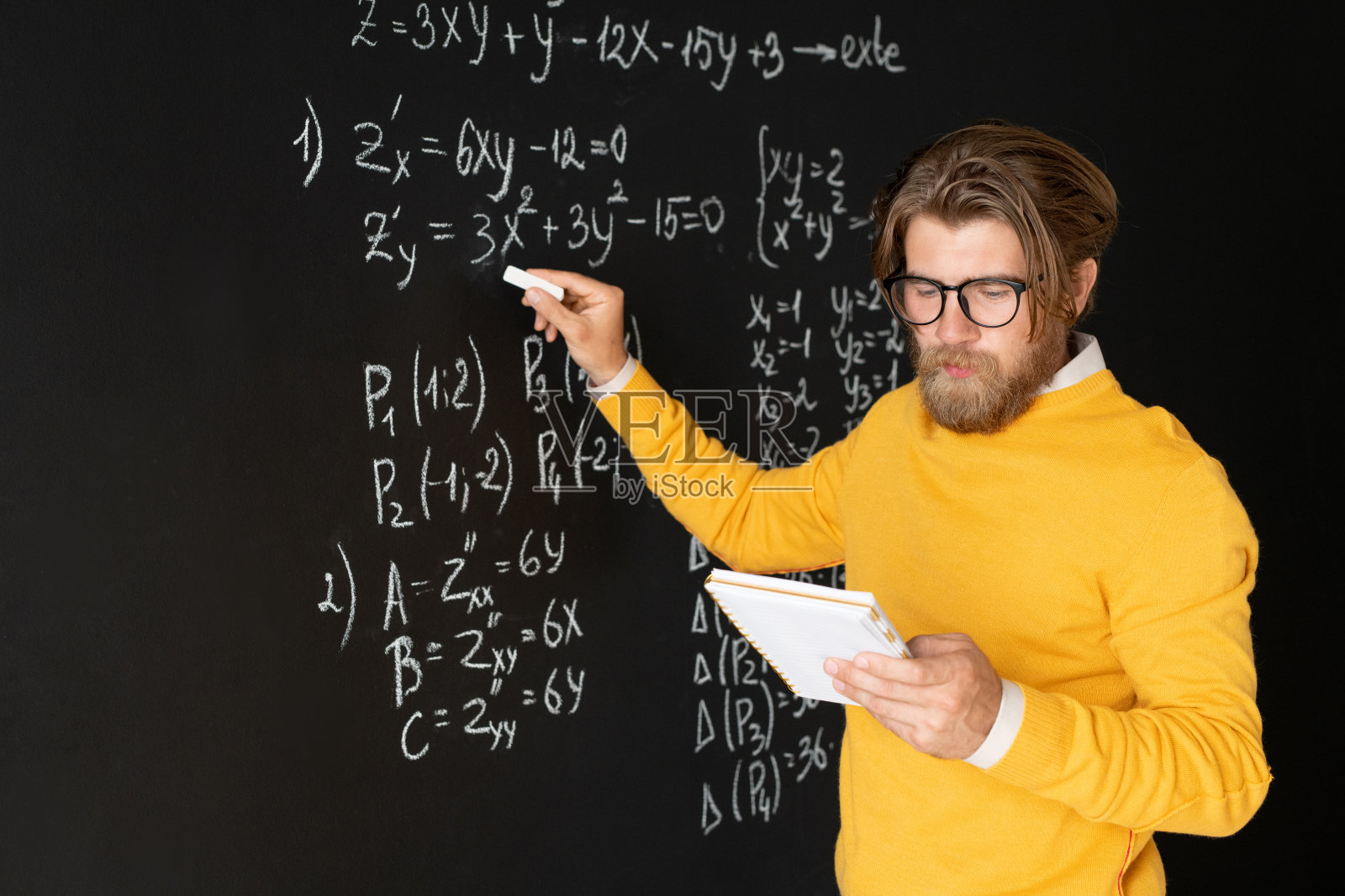 严肃的老师用粉笔指着黑板上的方程式照片摄影图片