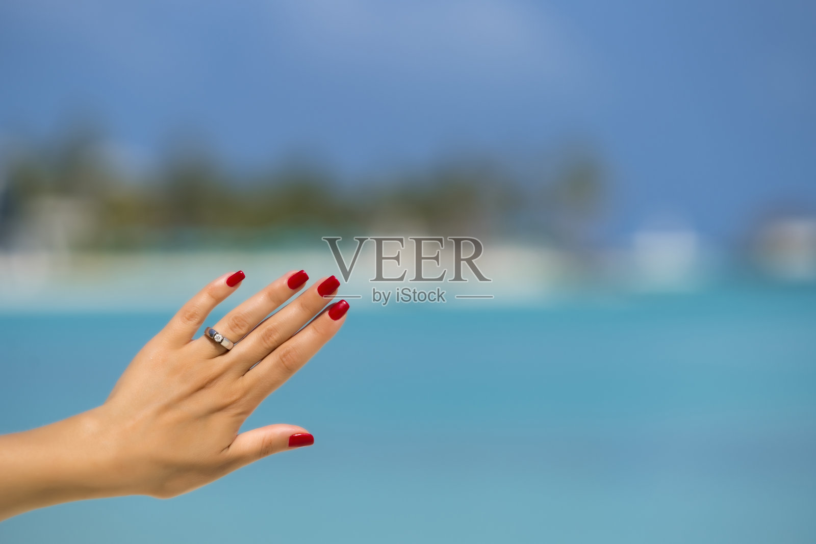 近距离的女人手指显示订婚戒指在热带海滩上。人的关系，戒指礼物，爱情和蜜月的概念在度假村。照片摄影图片