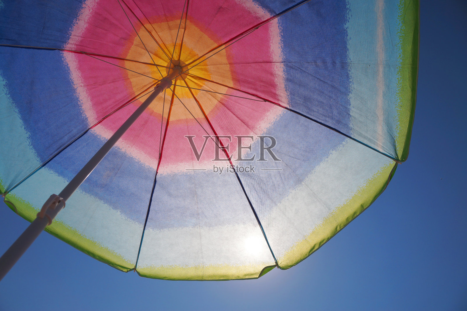 阳光透过一把色彩斑斓的沙滩伞照片摄影图片