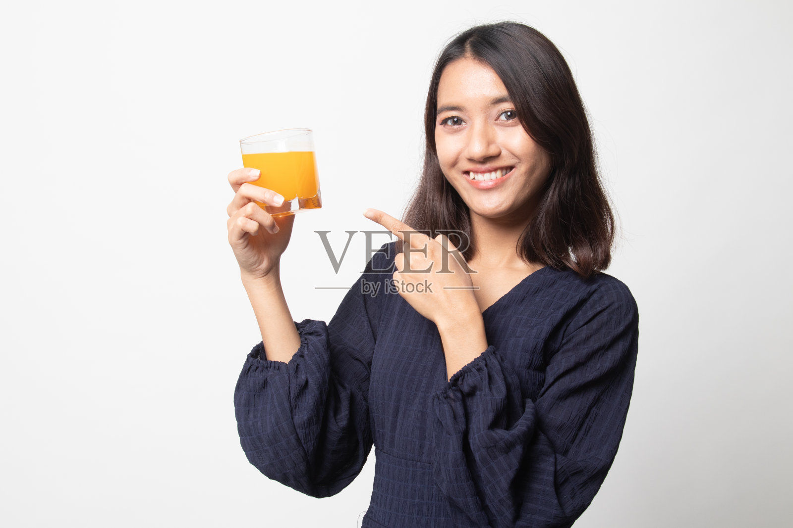 年轻的亚洲女人指着橙汁。照片摄影图片