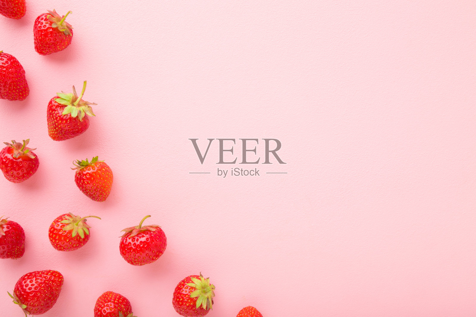 亮红色的草莓在浅粉色的桌子背景上。美丽的新鲜浆果。柔和的颜色。平的。文本的空位置。自顶向下的观点。照片摄影图片