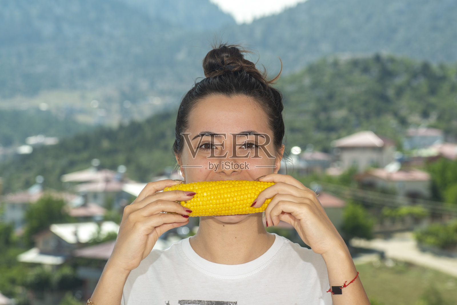 年轻女孩在吃玉米。在户外吃零食。照片摄影图片