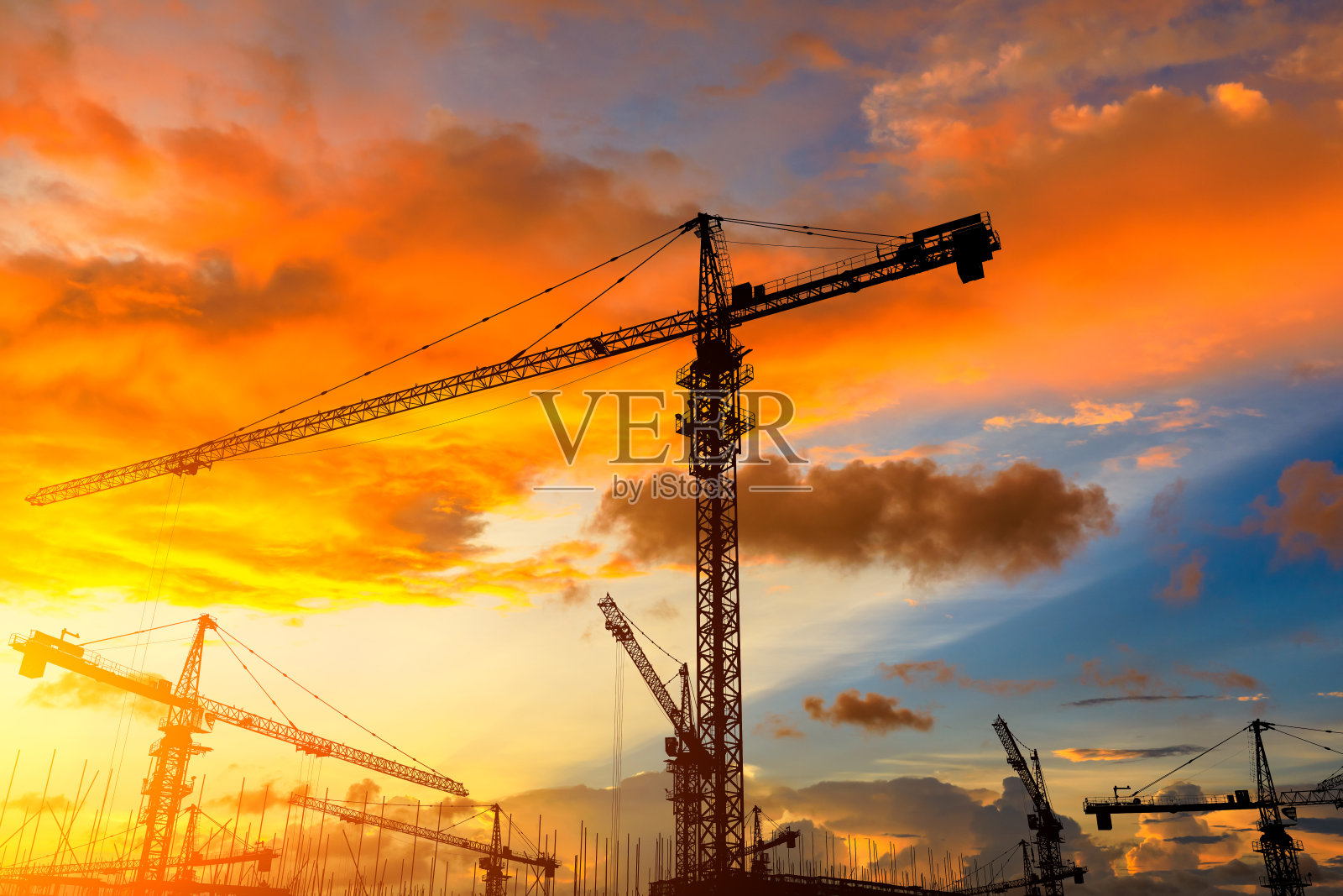 日出时塔吊和建筑工地的剪影。照片摄影图片