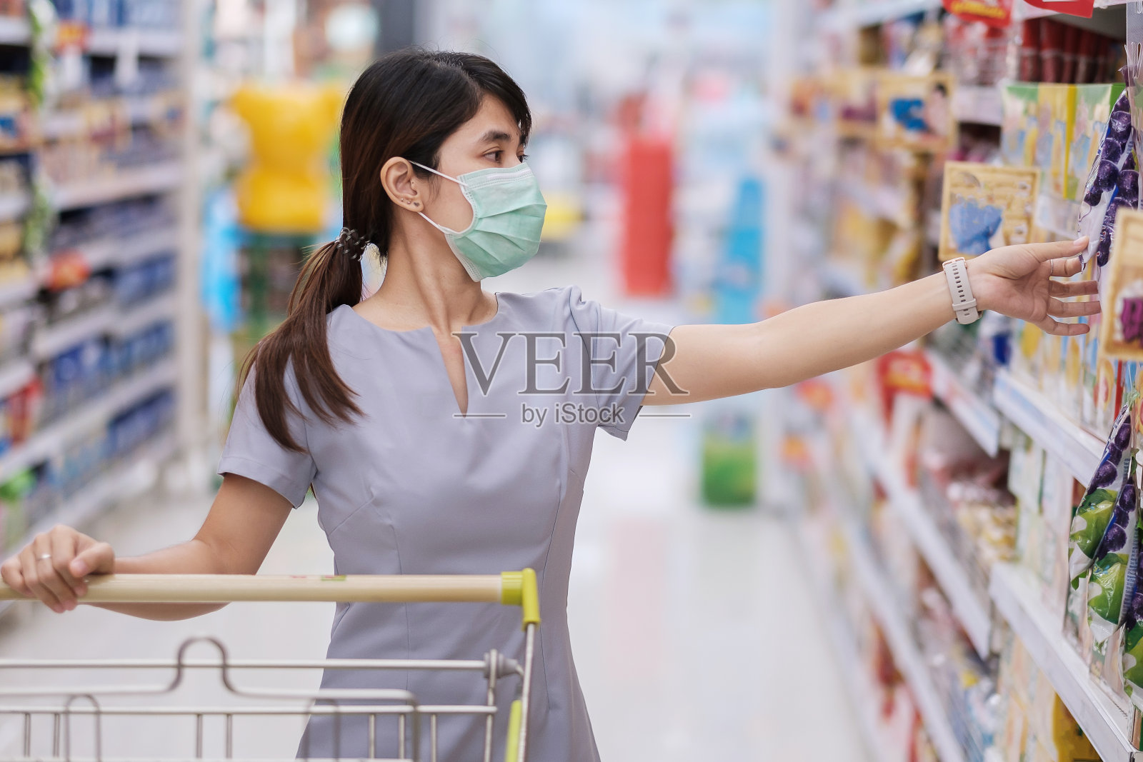 年轻妇女戴上防护口罩并在杂货店或百货商店购物可以保护冠状病毒感染。社交距离、新常态和2019冠状病毒病大流行下的生活照片摄影图片