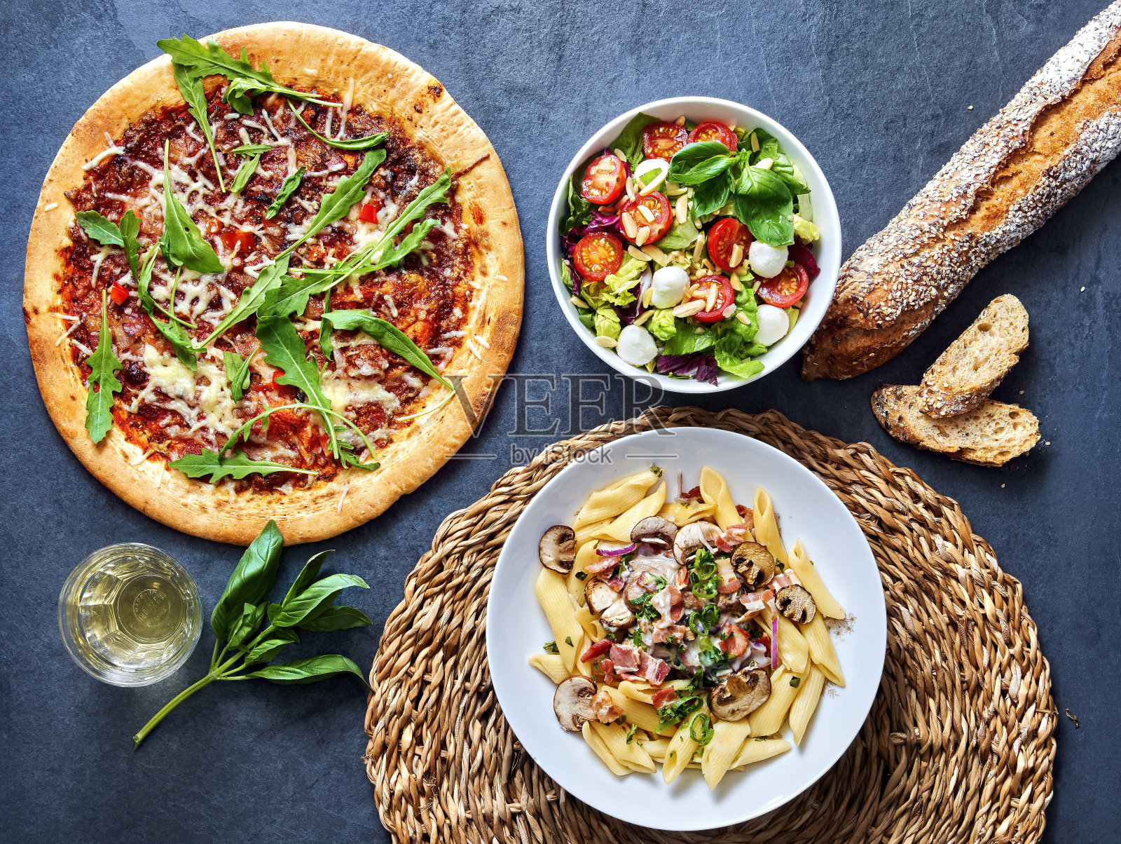 披萨，沙拉和意大利面可以在地下的石头上吃。照片摄影图片