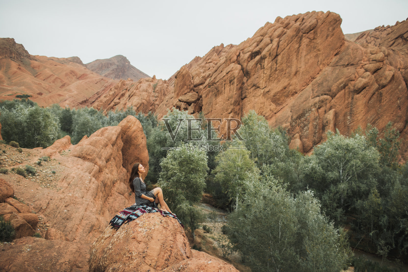 妇女坐在东方地毯上的背景Todra峡谷峡谷在摩洛哥。与自然和谐、自由的理念。嬉皮士生活方式。照片摄影图片
