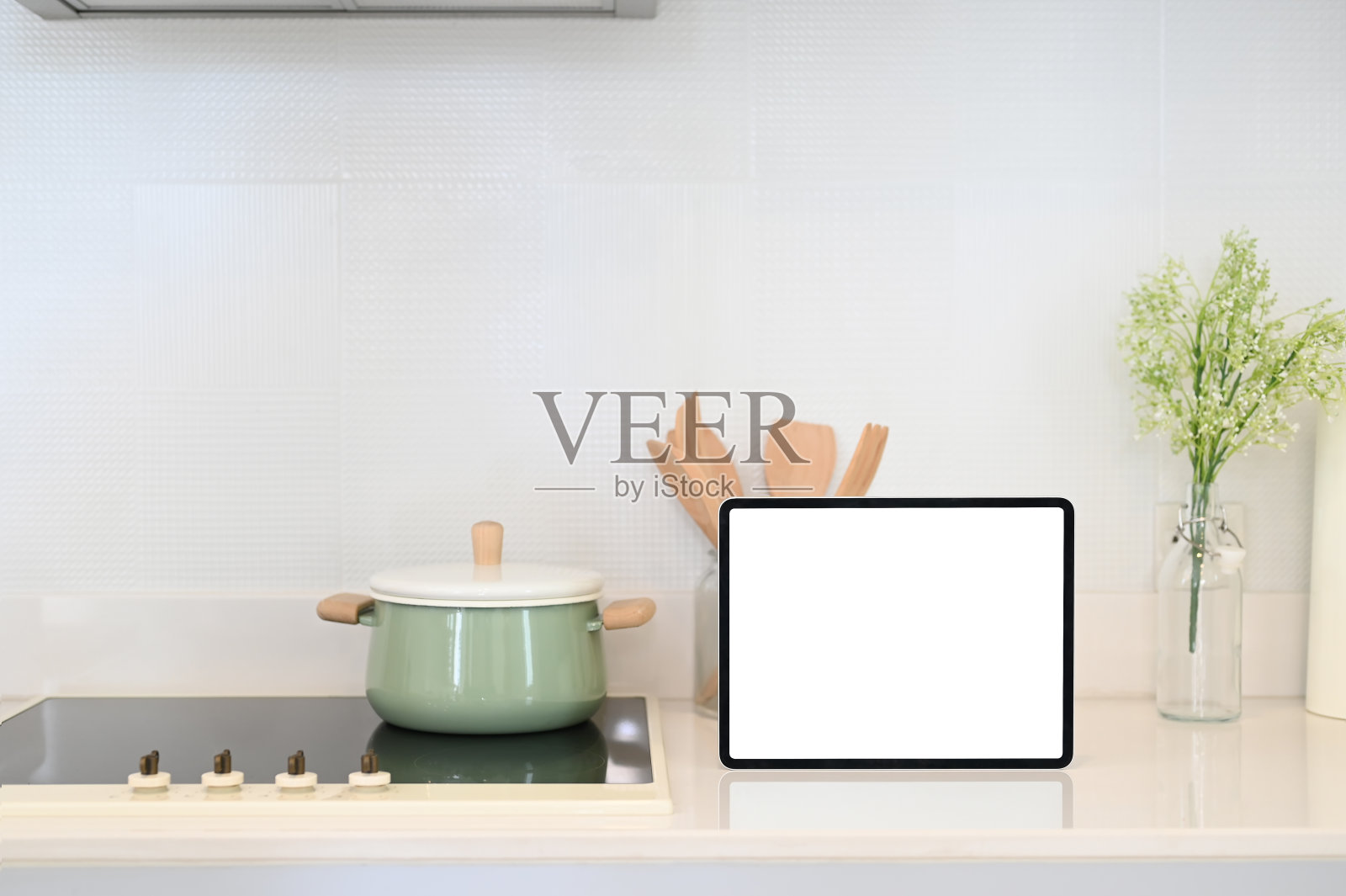 现代厨房柜台上的白色屏幕的厨具和平板电脑。照片摄影图片
