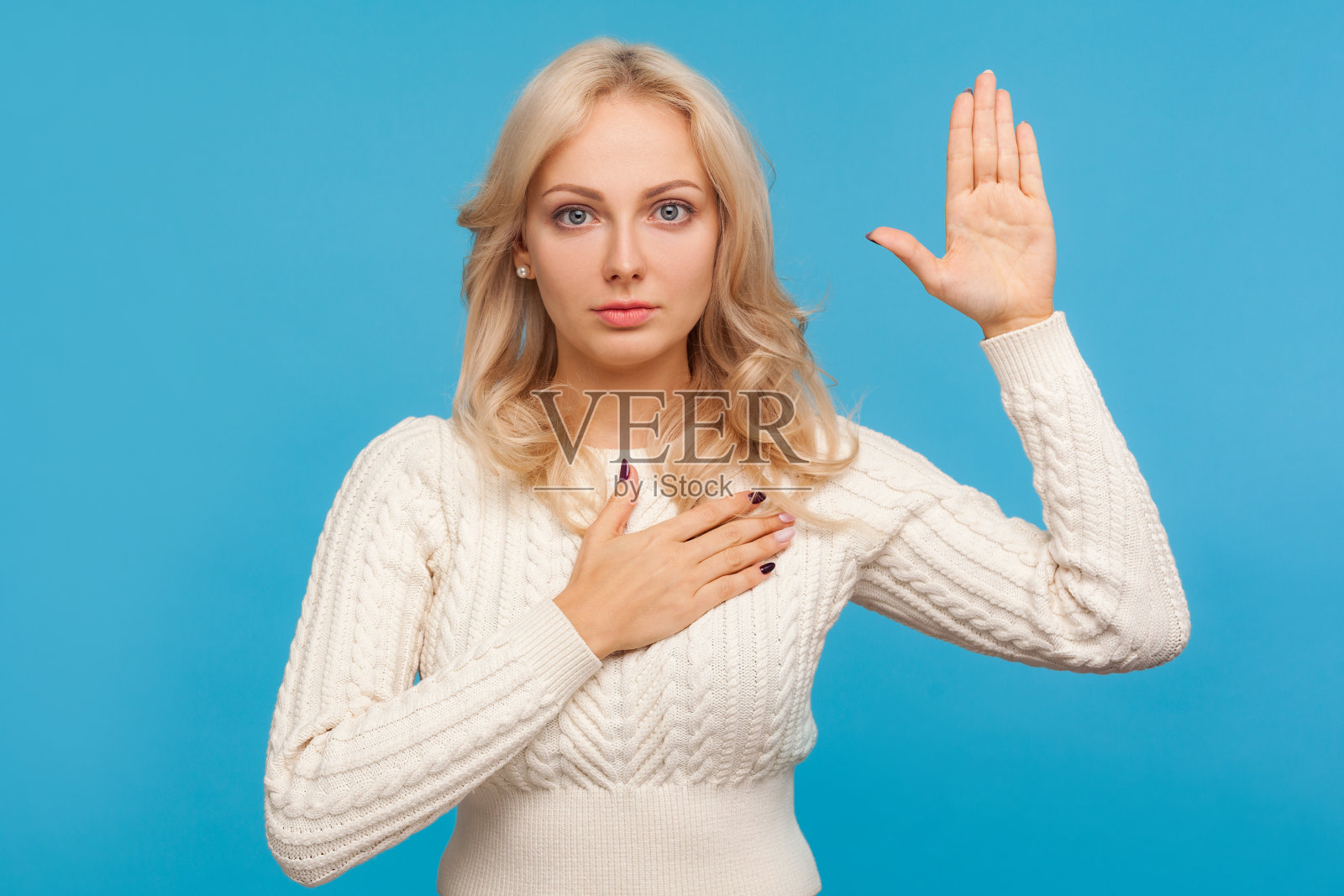 一头金色卷发的严肃爱国妇女抬起一只手臂，把另一只手臂放在胸前，发誓照片摄影图片