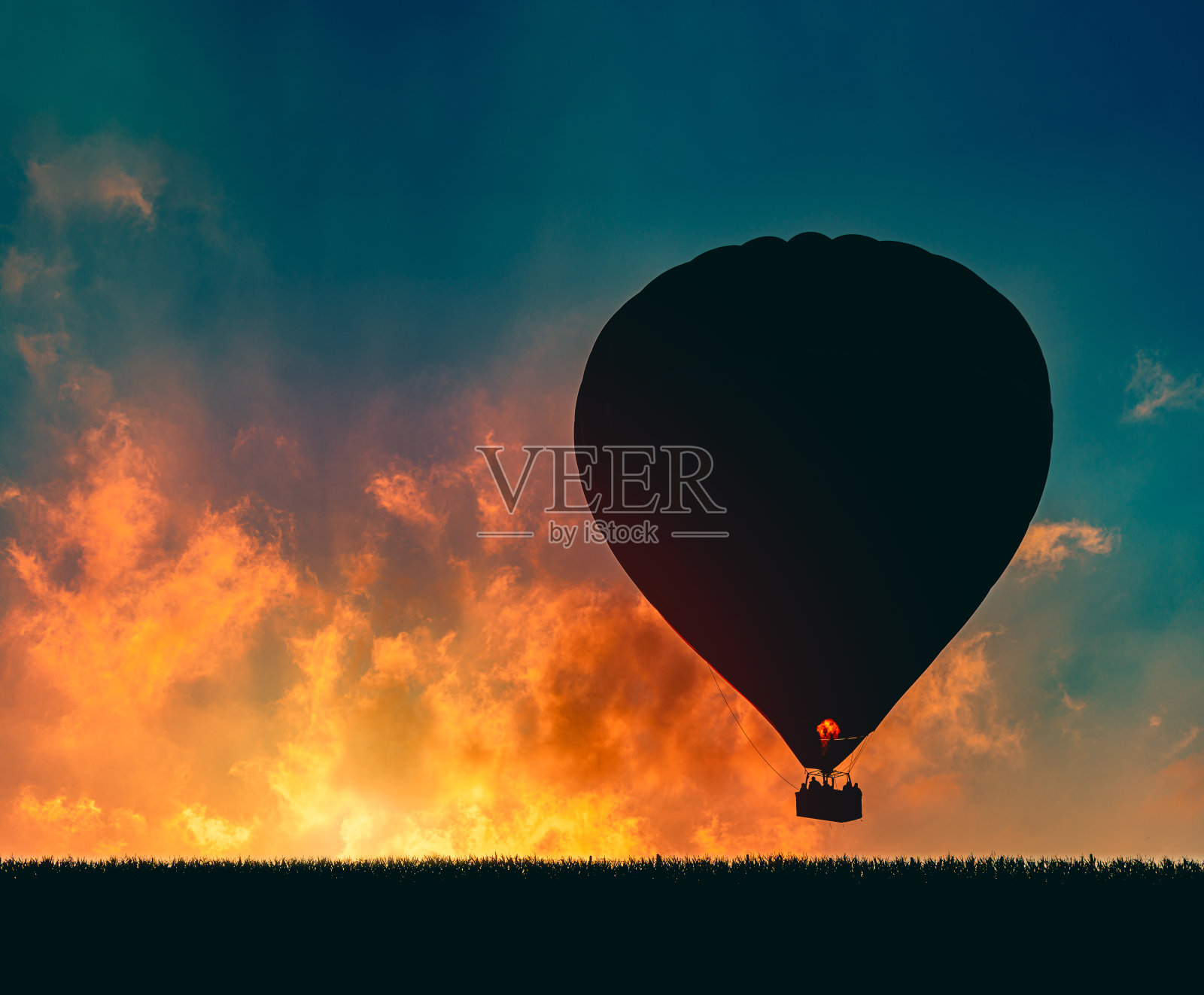 德国日落时热气球的剪影。草地和地面在前景与日落的天空和云在背景照片摄影图片