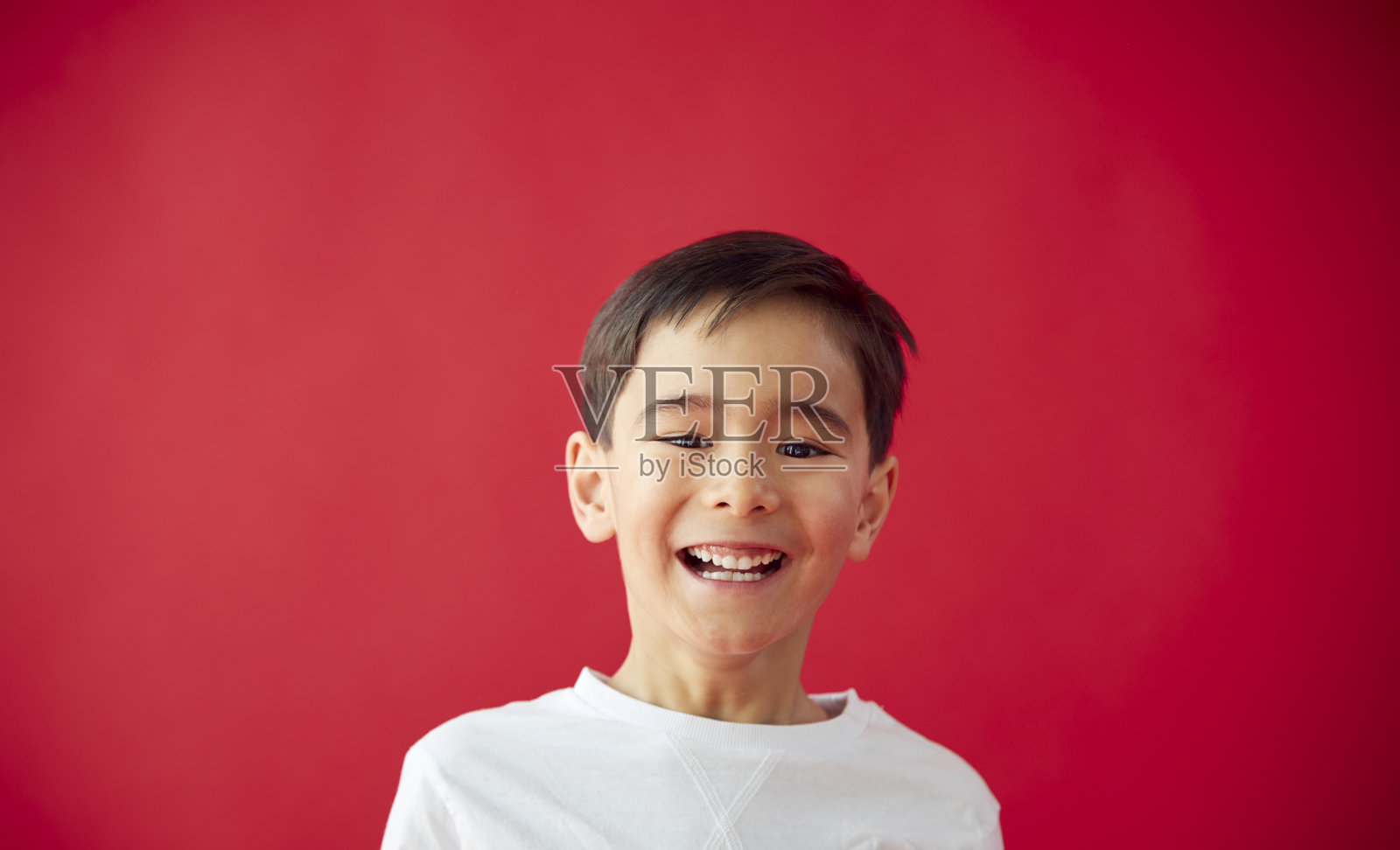 在红色演播室背景下微笑的小男孩的肖像照片摄影图片