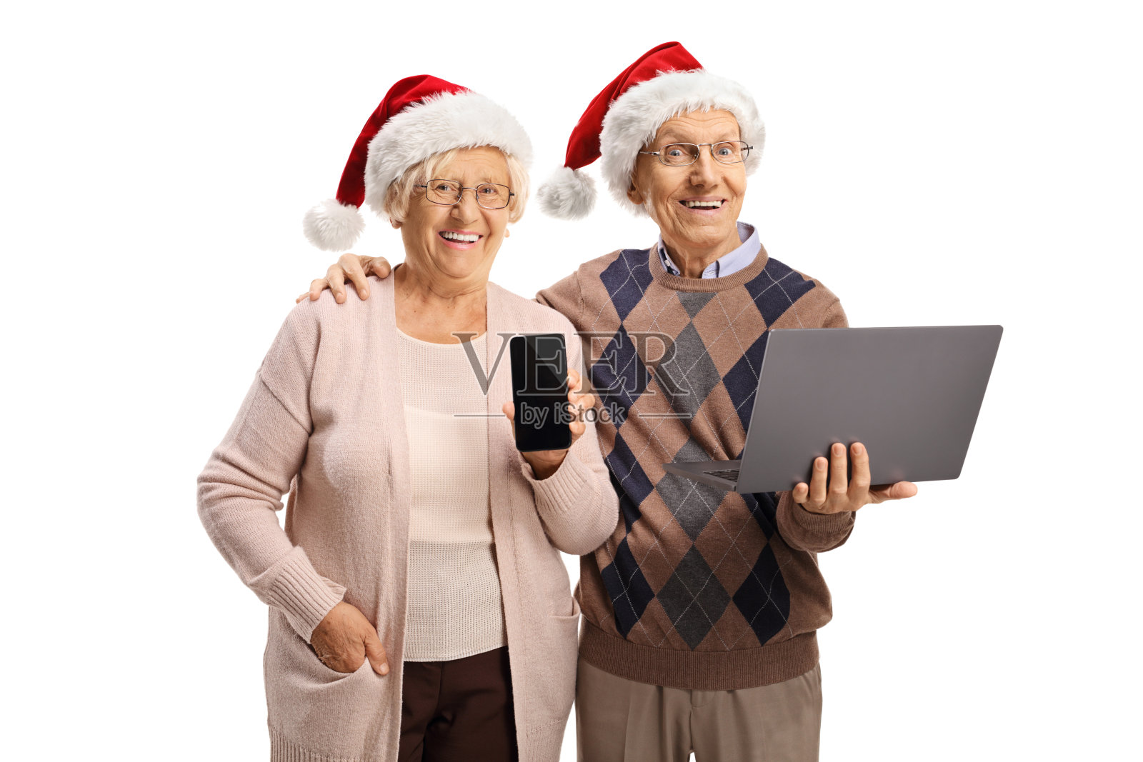 戴着圣诞帽、手持笔记本电脑和智能手机的快乐老人和老人照片摄影图片