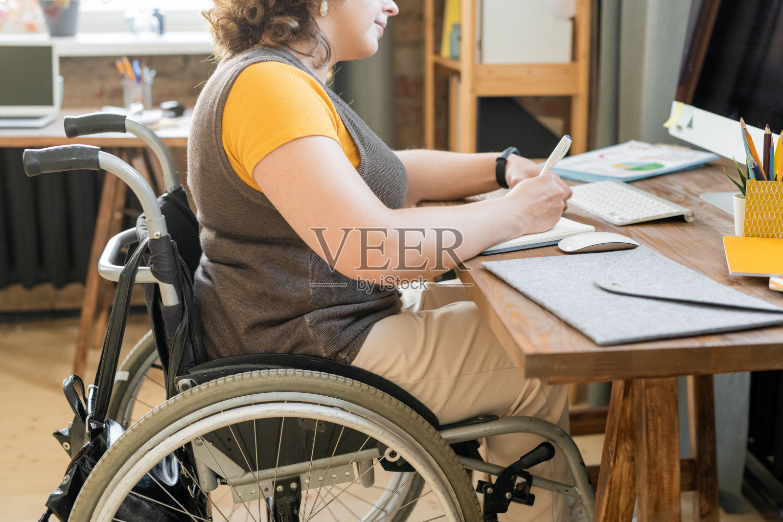 年轻的女经理穿着休闲装坐在电脑前的轮椅上照片摄影图片