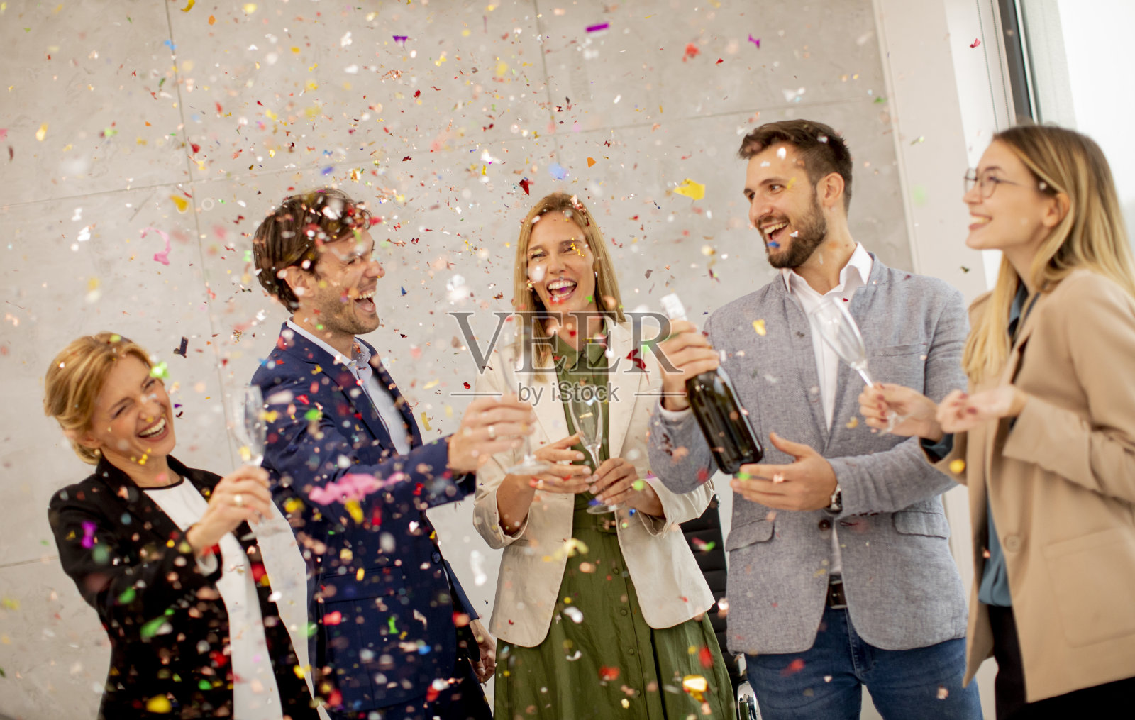 一群商业人士庆祝和祝酒，五彩纸屑散落在办公室里照片摄影图片