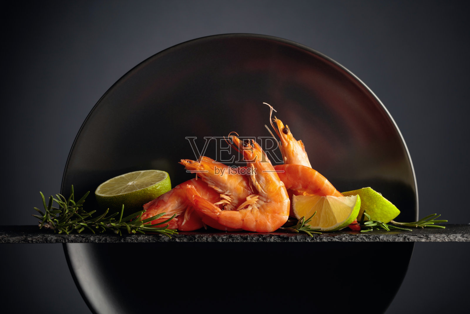 煮虾，迷迭香和酸橙在黑色的背景。照片摄影图片
