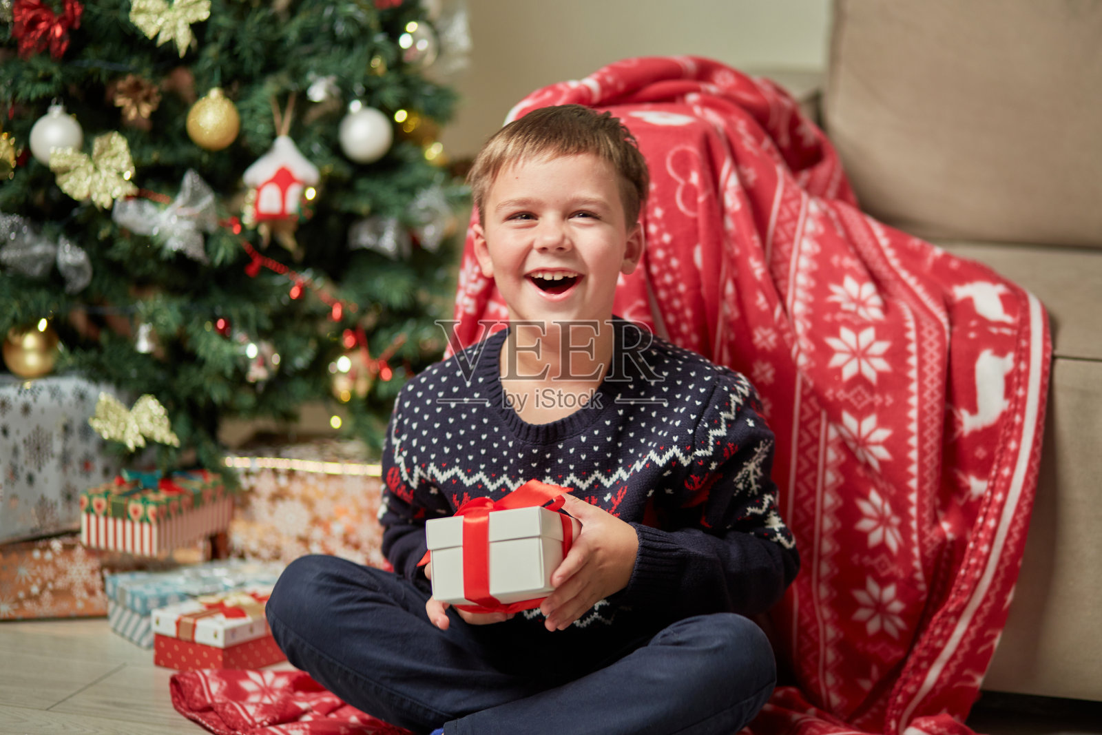 一个穿着毛衣的男孩笑着手里拿着一份礼物。照片摄影图片