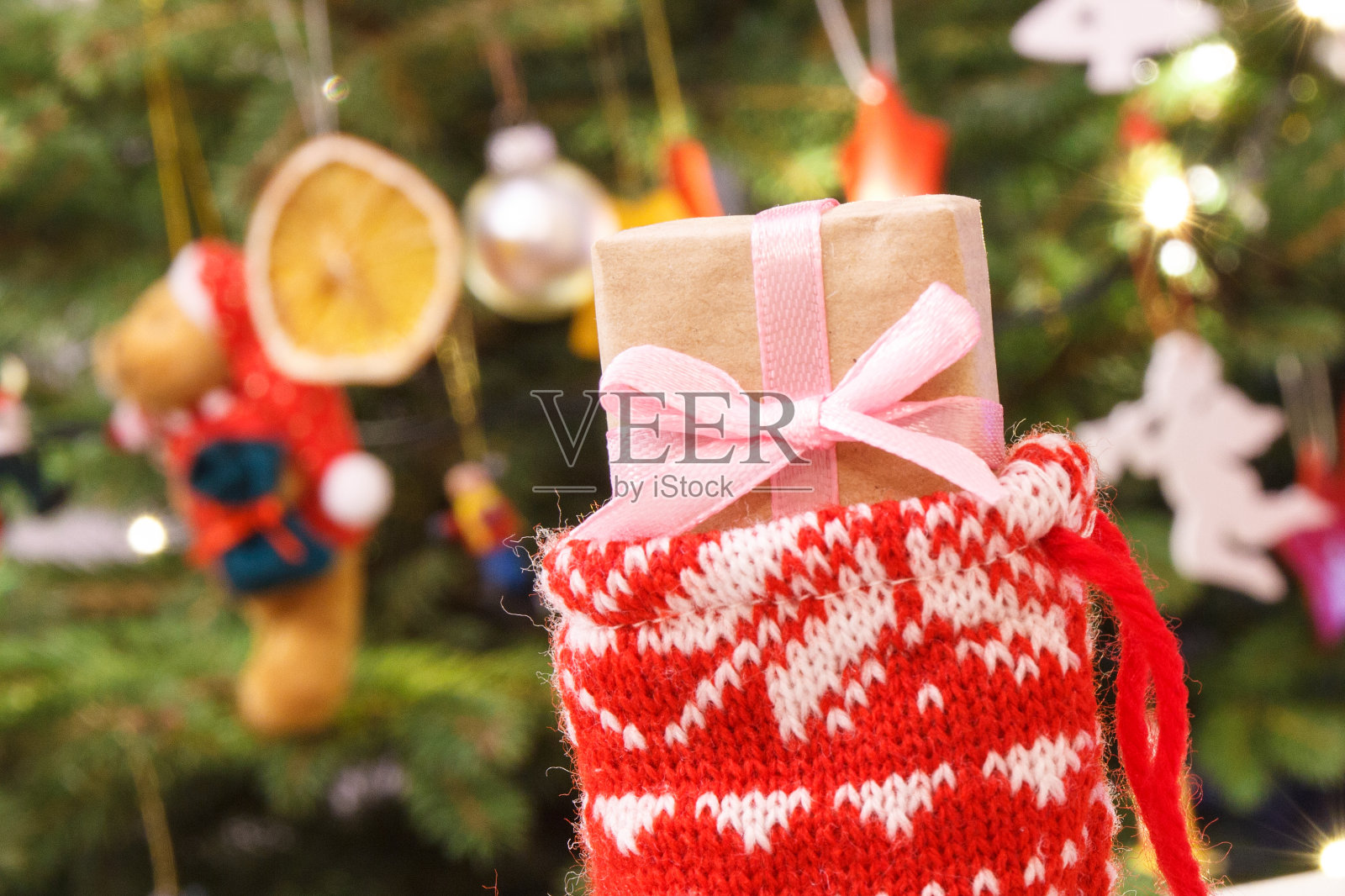 用丝带包裹的圣诞礼物在红色袜子的背景上用圣诞树装饰照片摄影图片
