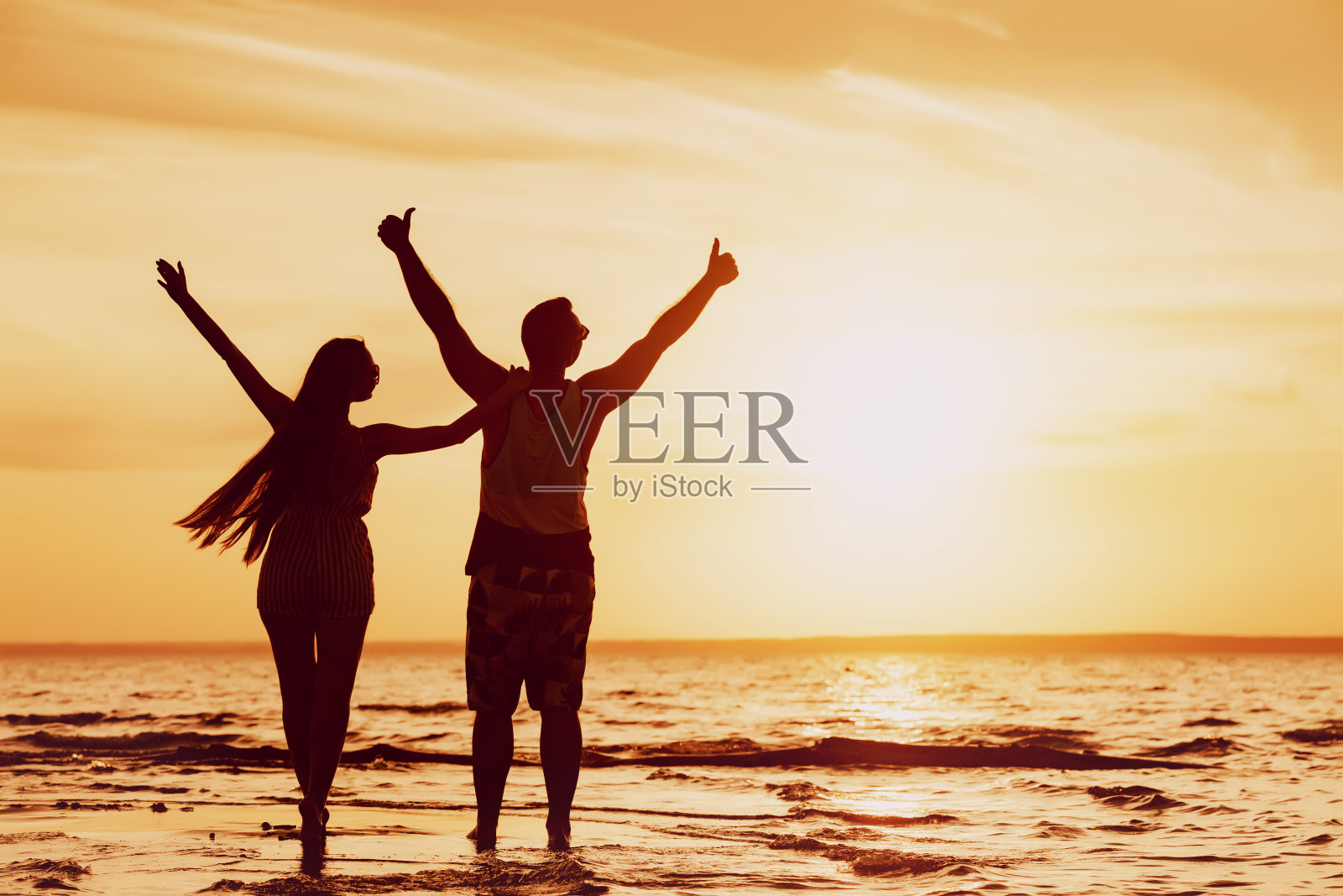 日落海滩上举起双手的幸福夫妇照片摄影图片